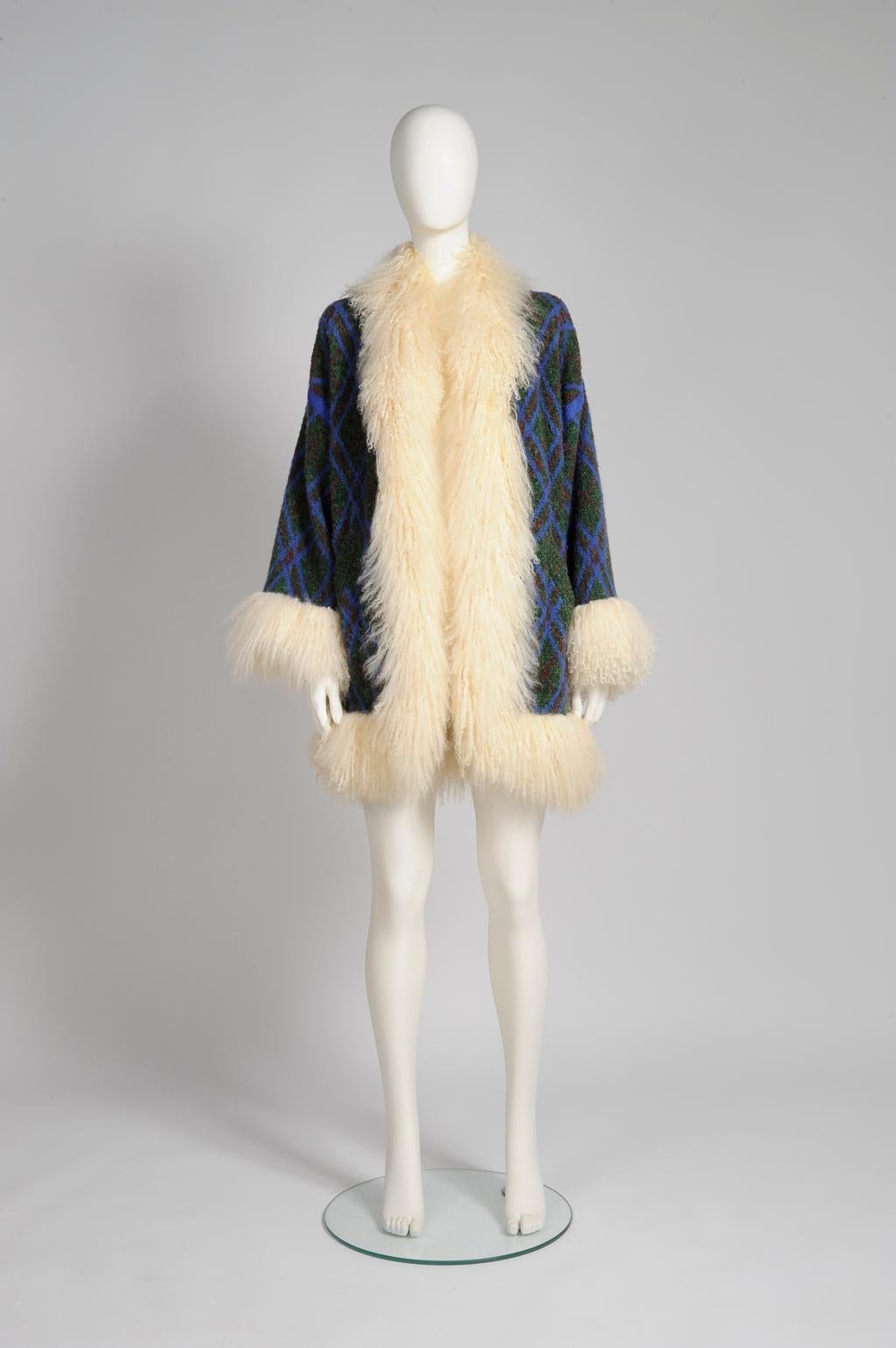 What an unusual and fantastic piece by Monsieur Saint Laurent ! Knitted of cozy wool (40%) and mohair (35%), this rare unlined cardigan-coat is trimmed with genuine ivory fuzzy Mongolian sheep fur. Of versatile green, blue and bordeaux colors, it
