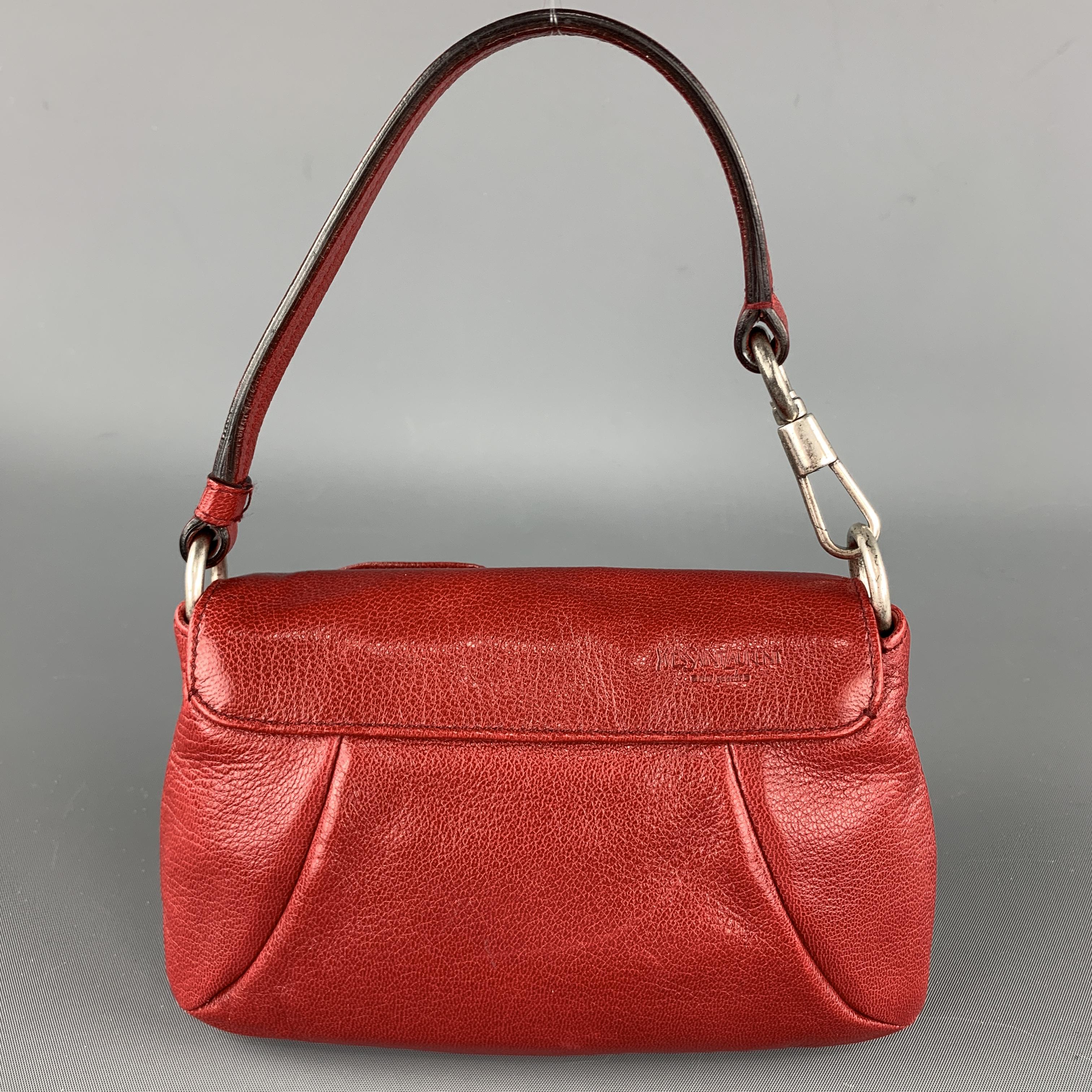 Vintage YVES SAINT LAURENT Rive Gauche Nadja Shoulder / Wrist Bag comes in a red tone in a solid leather material, with a ruched flower at flap, silver metal tone hardware, a brown silk lining, and a inner pocket. Light wear at strap closure. Made