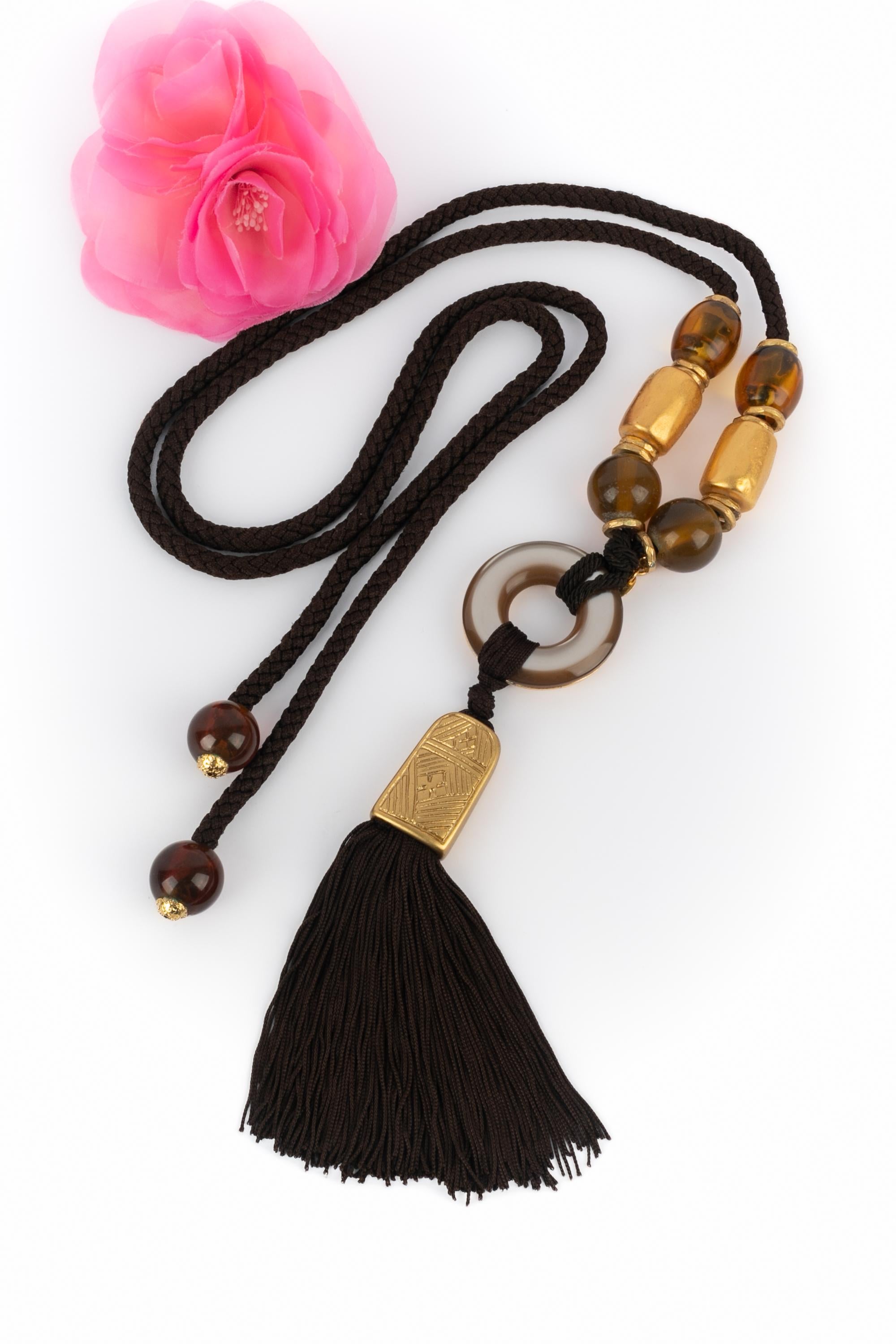 Yves Saint Laurent - (Made in France) Collana lunga decorata con perle di resina trasparenti e dorate e un pompon marrone. Una collezione del 1990 circa sotto la direzione artistica di Yves Saint Laurent.

Condizioni:
Ottime