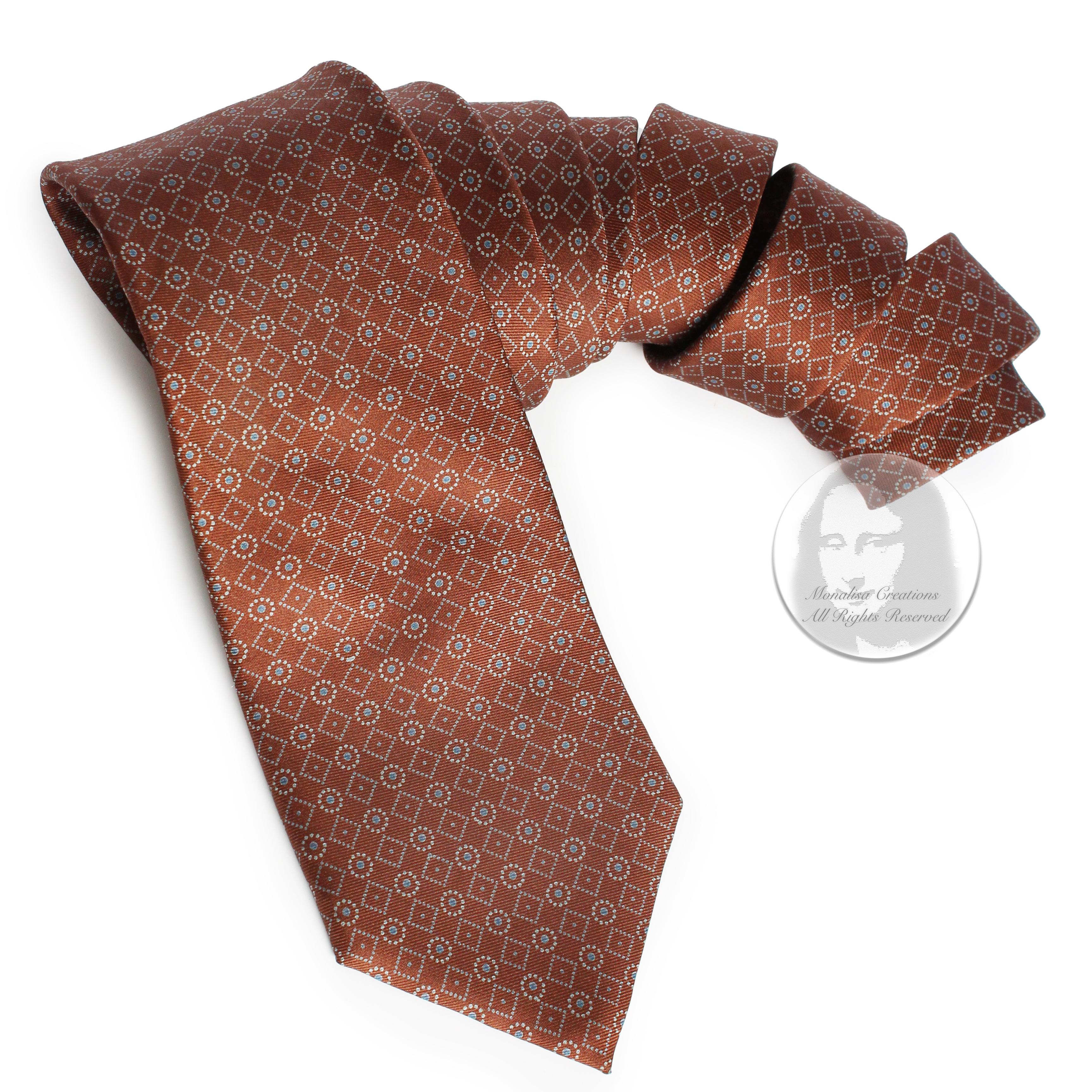 Authentic, preowned, vintage Yves Saint Laurent necktie, most likely made in the 1970s. Made from silk, it features a Moroccan influenced abstract pattern of dotted circles and diamond shapes in pale blue against a red-hued brown background.  

It's