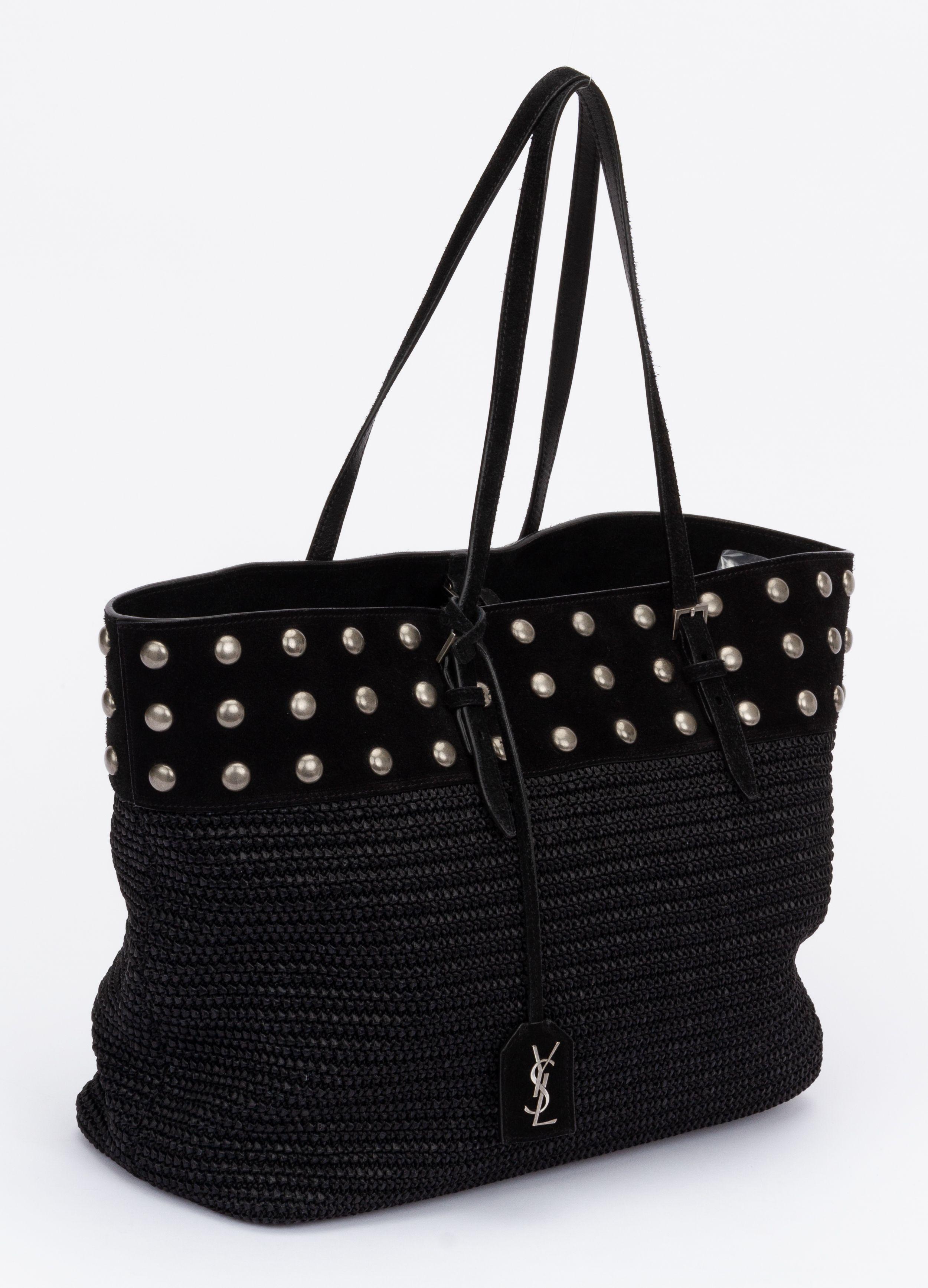 Yves Saint Laurent tote in black crafted of wicker. Perfect piece for the beach or an everyday bag. The bottom half of the bag is black wicker while the top half is decorated with studs in silver hardware. It has to handles (8.5