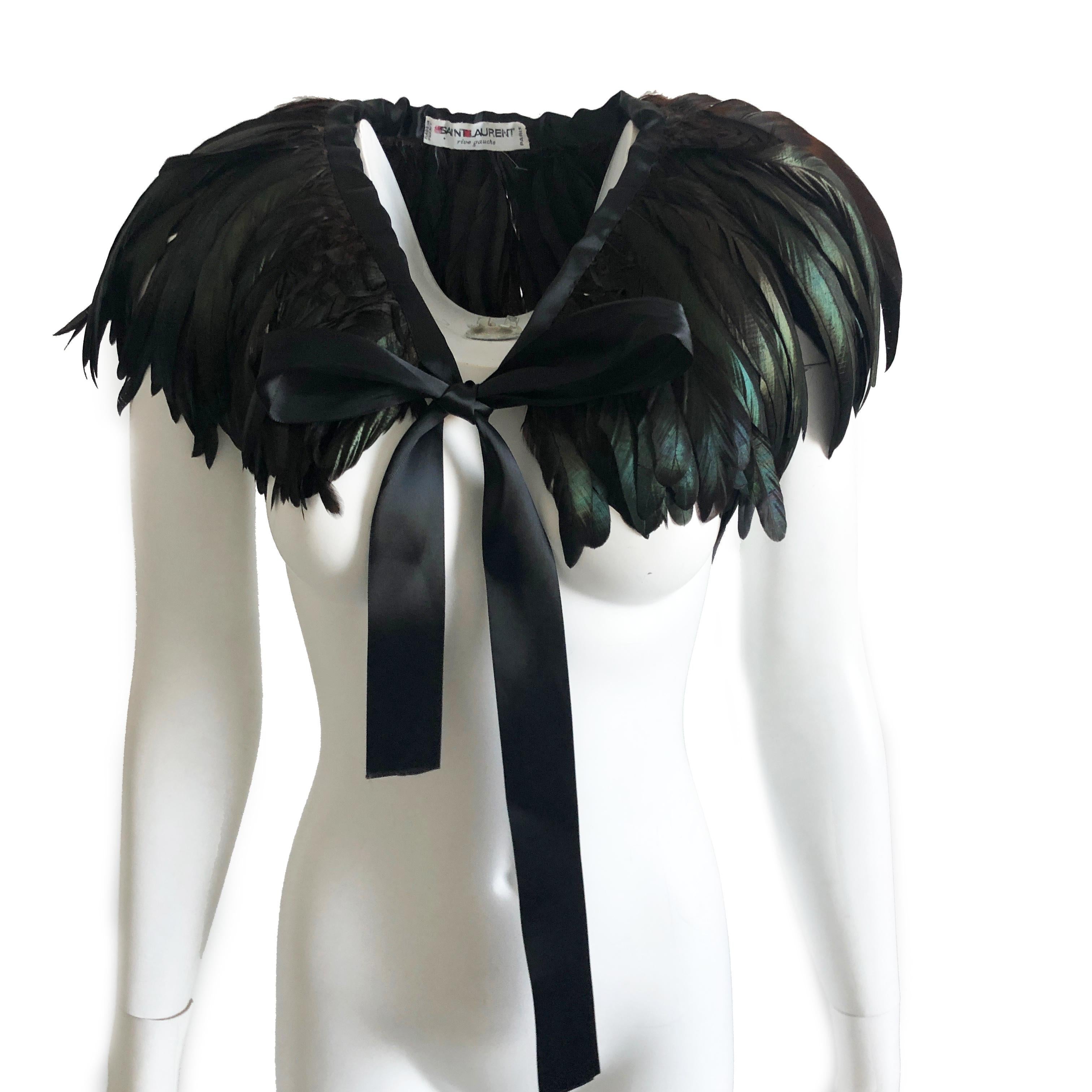 This incredible feathered cape or oversized collar was made by Yves Saint Laurent in the late 1970s. Constructed with iridescent emerald, bronze and black feathers, this piece fastens with long black silk ties. Preowned/vintage with minimal signs of