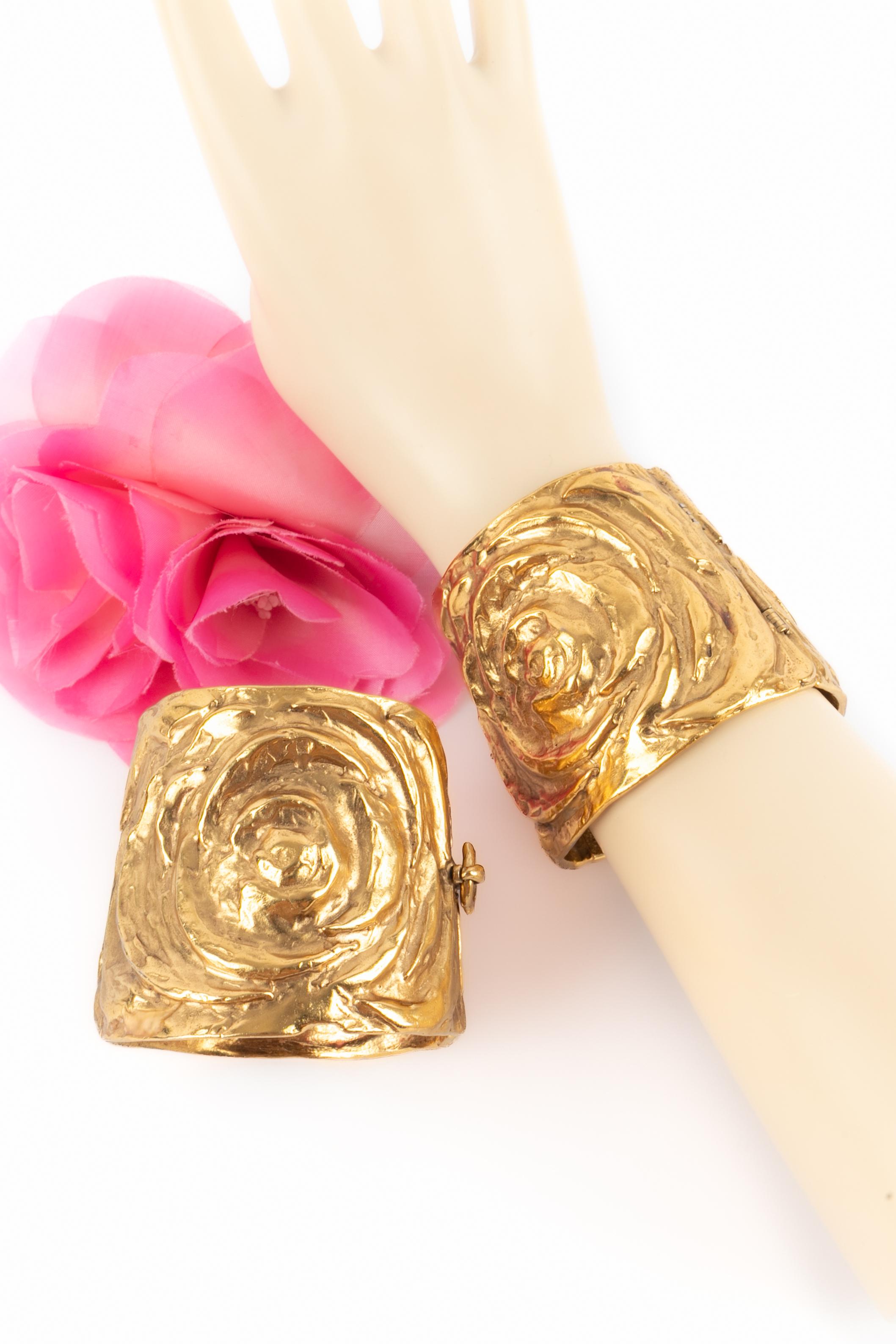 YVES SAINT LAURENT - Pair of golden metal cuff bracelets with circular decorations. Work from the Robert Goossens Atelier - a collection circa 1980.

Condition:
Very good condition

Dimensions:
Min. handle length: 15 cm - Max. handle length: 18