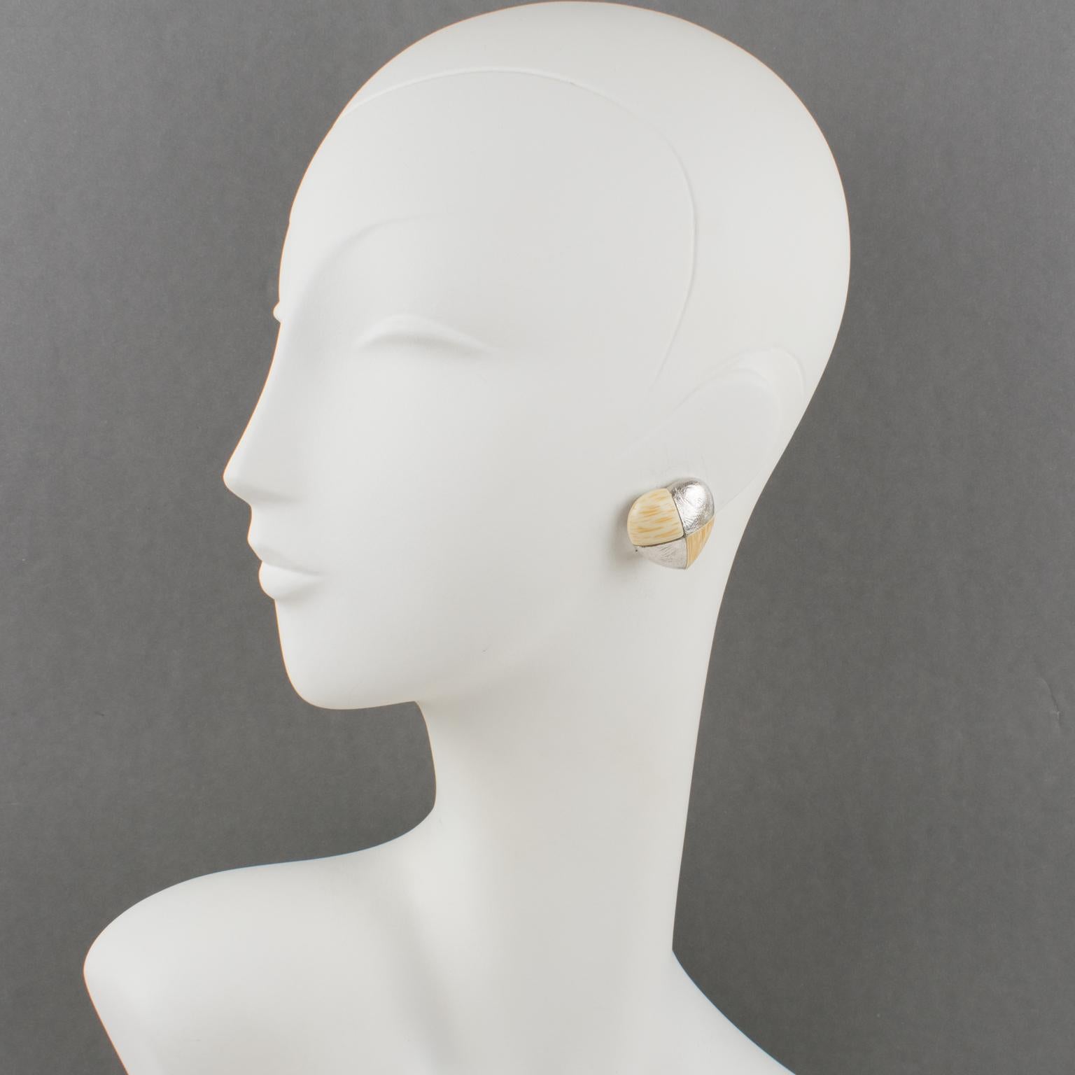 These elegant Yves Saint Laurent Paris signed clip-on earrings feature a romantic heart shape with textured silvered metal in a checkerboard pattern contrasted with off-white and beige resin elements with a textured pattern imitating bone. Each