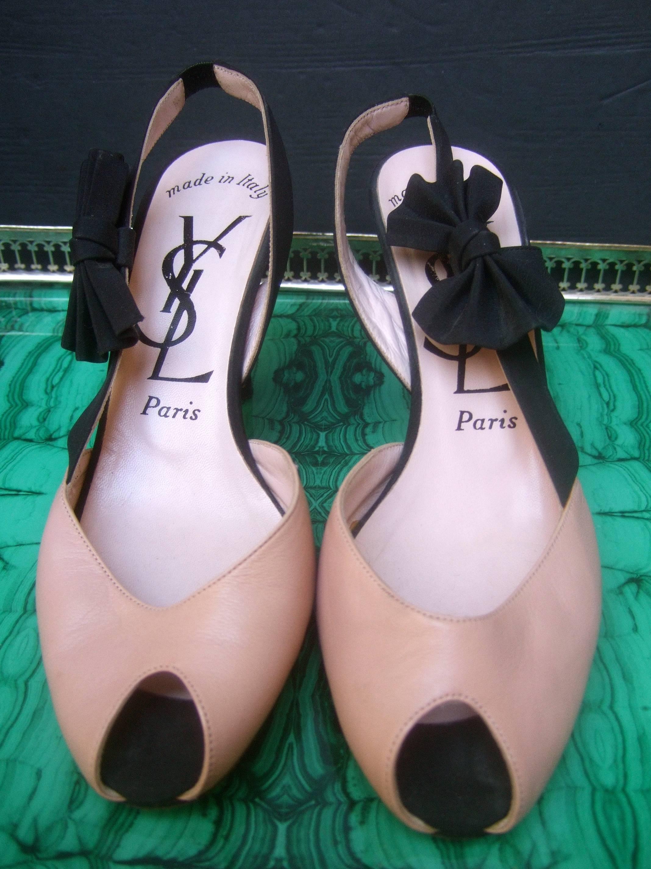 Yves Saint Laurent Paris leather peep toe pumps US Size 7.5 M
The Italian flesh tone leather shoes are accented with a black
cloth bow and matching black cloth covered heel 

Each shoe is accented with the black cloth bow detail 
The interior of the
