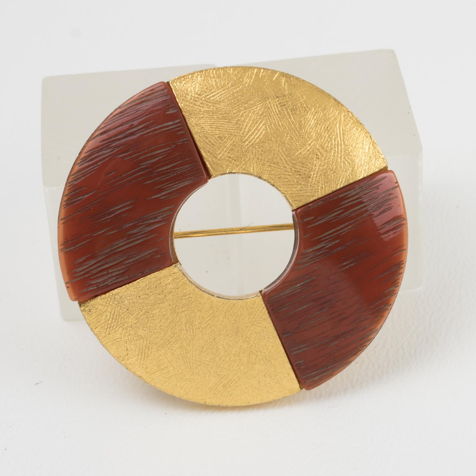 This lovely Yves Saint Laurent Paris signed pin brooch features a dimensional donut shape with textured gilt metal in a checkerboard pattern contrasted with rust resin elements with a texture imitating bone. The pin has a security closing clasp at