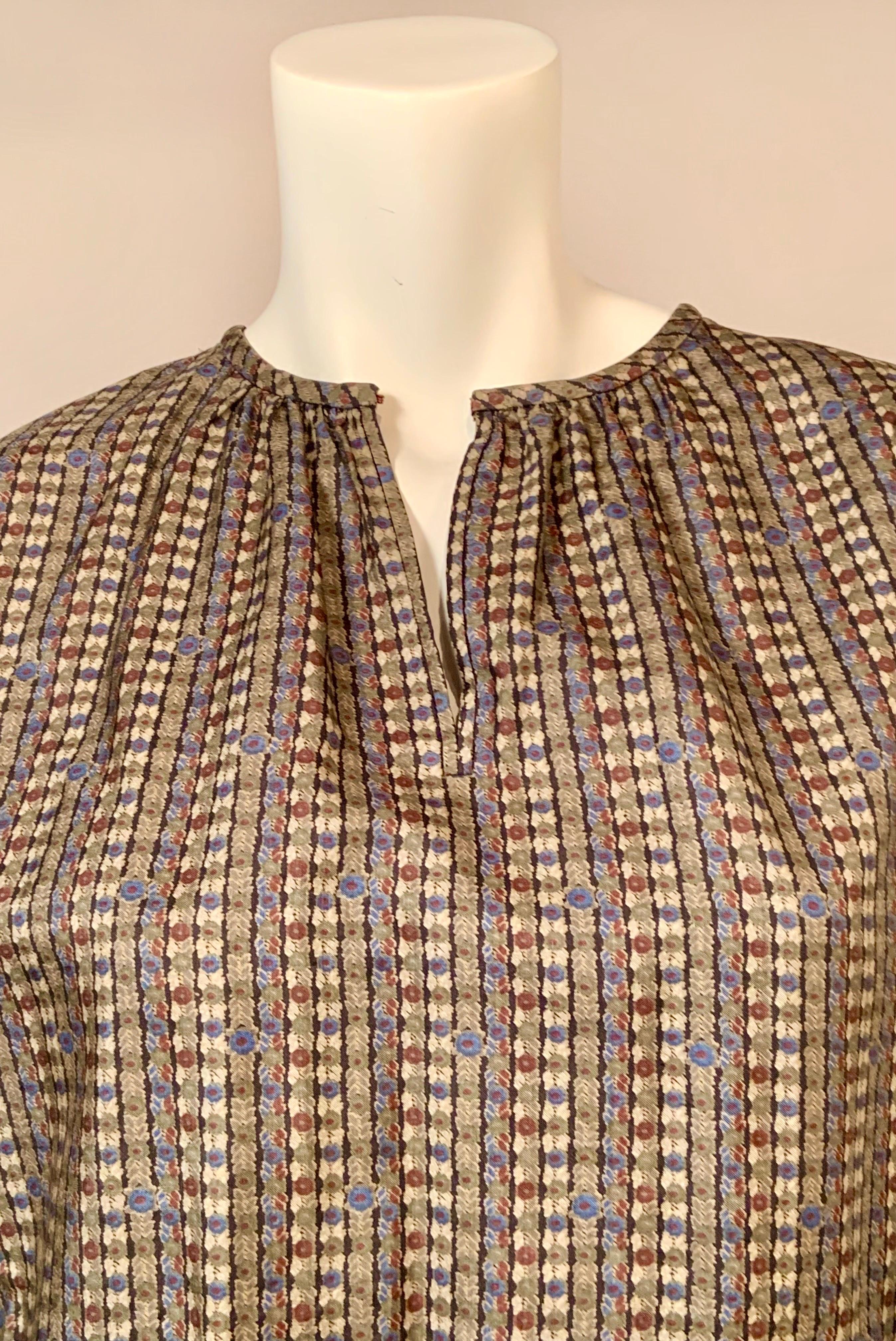 This printed silk peasant style blouse designed by Yves Saint Laurent for his Rive Gauche line has a neutral color pallet that will work with many pieces in your wardrobe.  The vertical print is divided by black lines.  There are shades of grey,