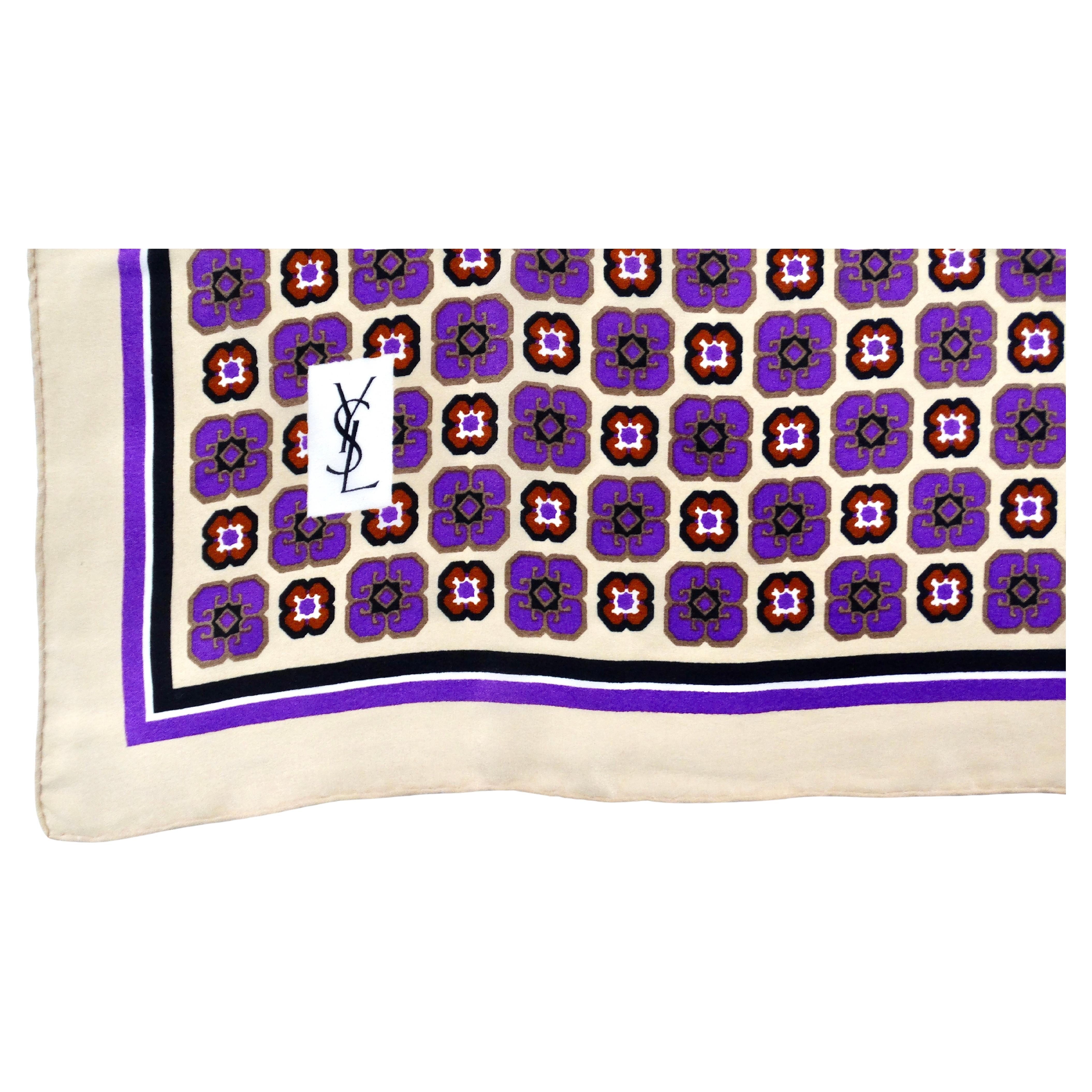 The 1980s Yves Saint Laurent Purple Floral Print Silk Scarf is a stunning accessory that exemplifies the luxurious elegance of that era. Crafted from sumptuous silk, it features a vibrant purple floral style motifs on a tan background, embodying the