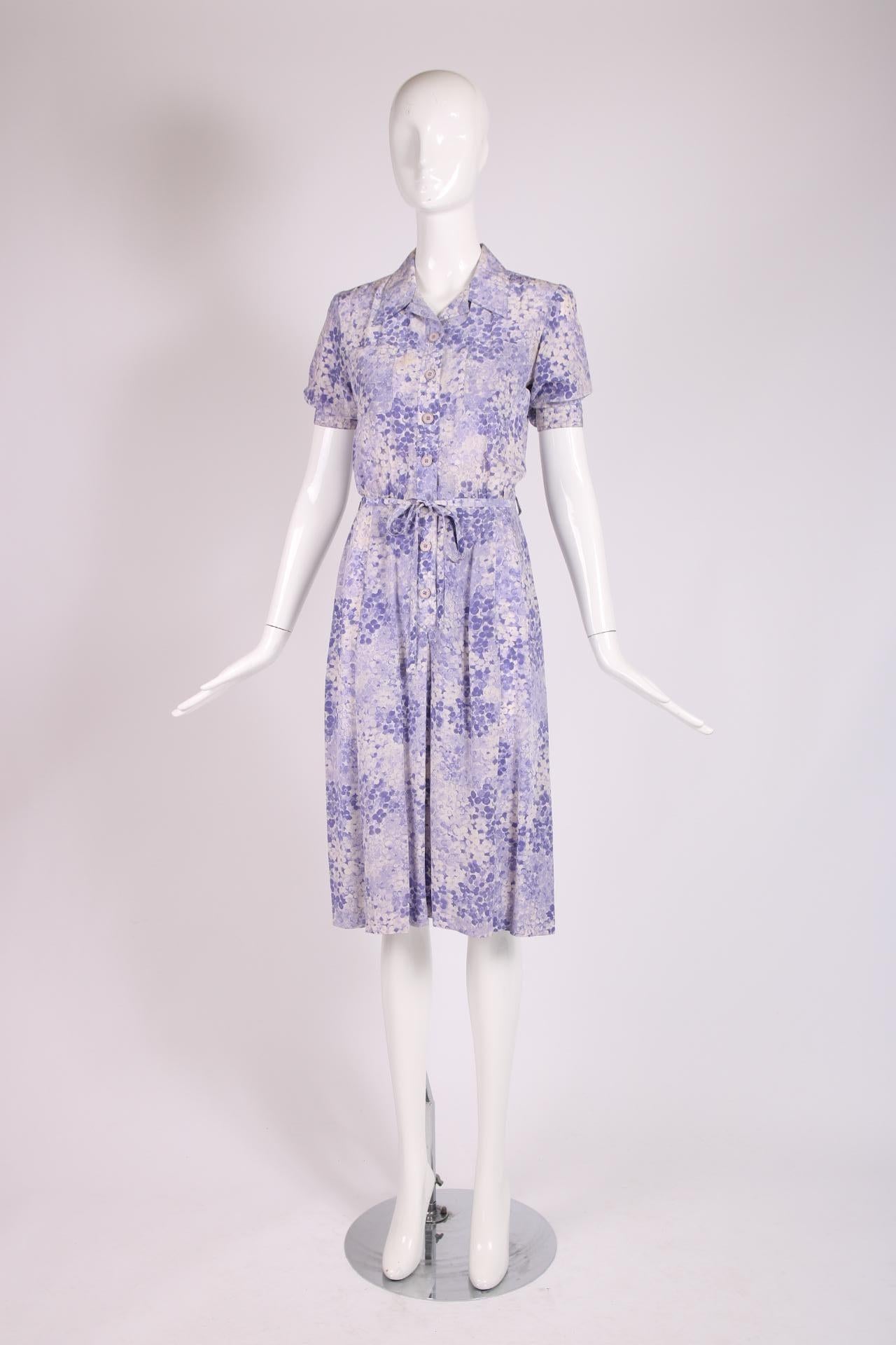 1970's Yves Saint Laurent purple floral print day dress with short sleeves, button closures down center front, frontal patch pockets, a self belt and a drop pleated skirt. 100% silk, in excellent condition. Size tag 40 but fits more like a modern