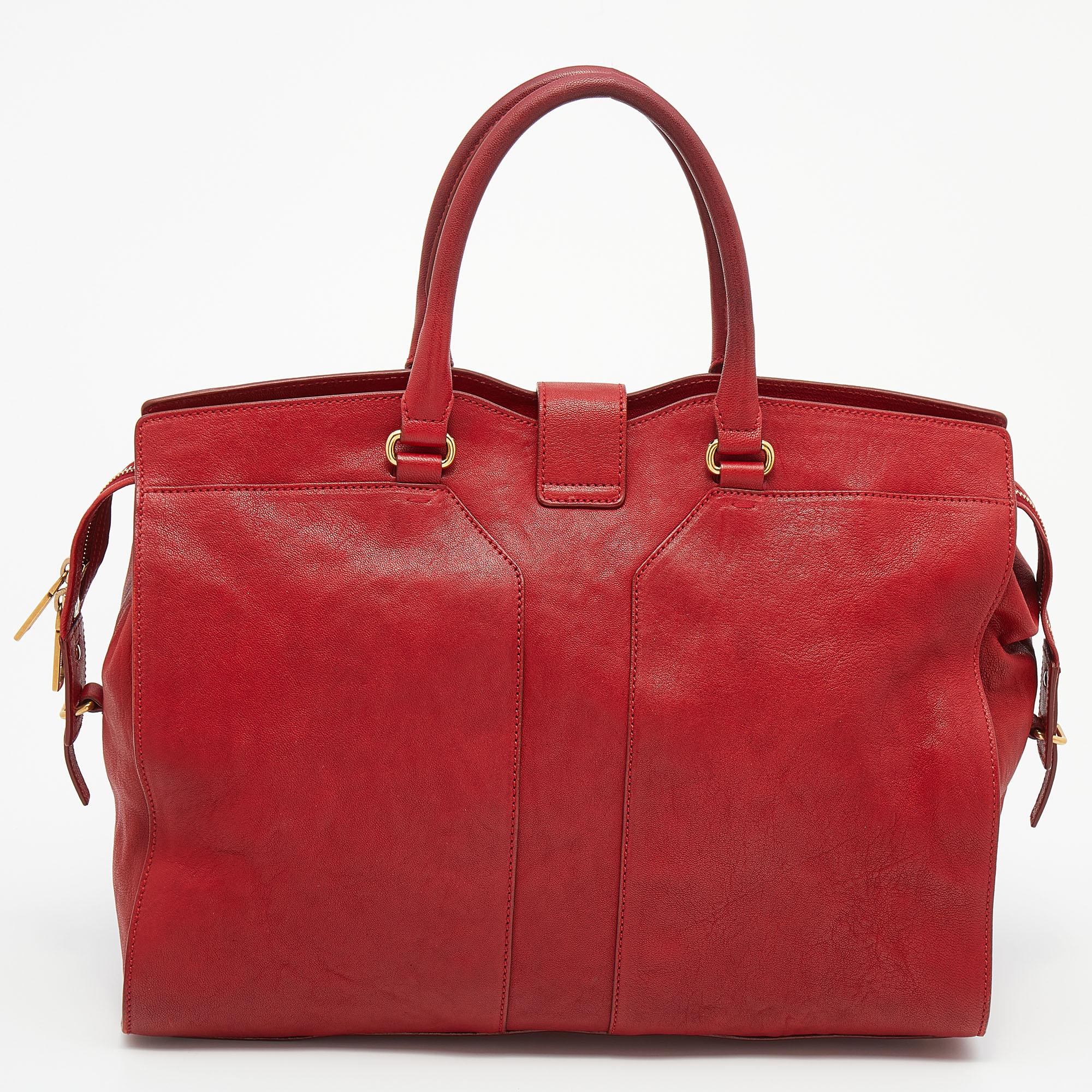 This elegant red Cabas Chyc tote from Yves Saint Laurent is ideal for everyday use. Crafted from leather, the bag is detailed with a gold tone hardware Y motif snap closure and dual-rolled handles. The top zip closure opens to a spacious interior