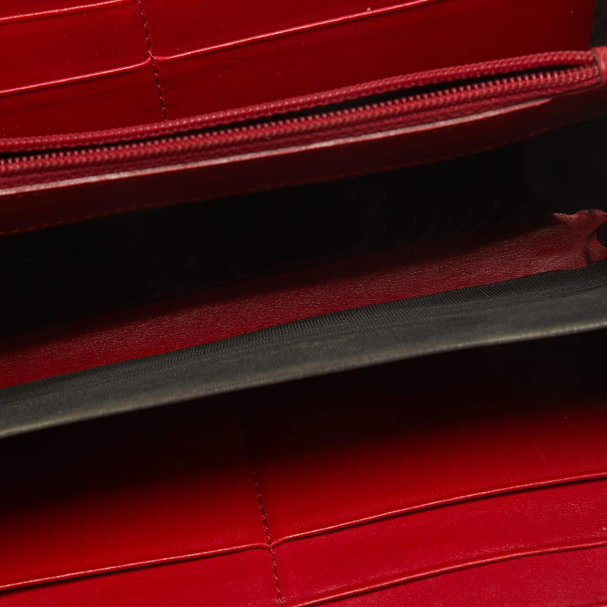 The logo detail on the front adds an exclusive touch to this Yves Saint Laurent clutch. Made from red patent leather it is complemented with gold tone hardware a flap closure and a compartmentalized interior.