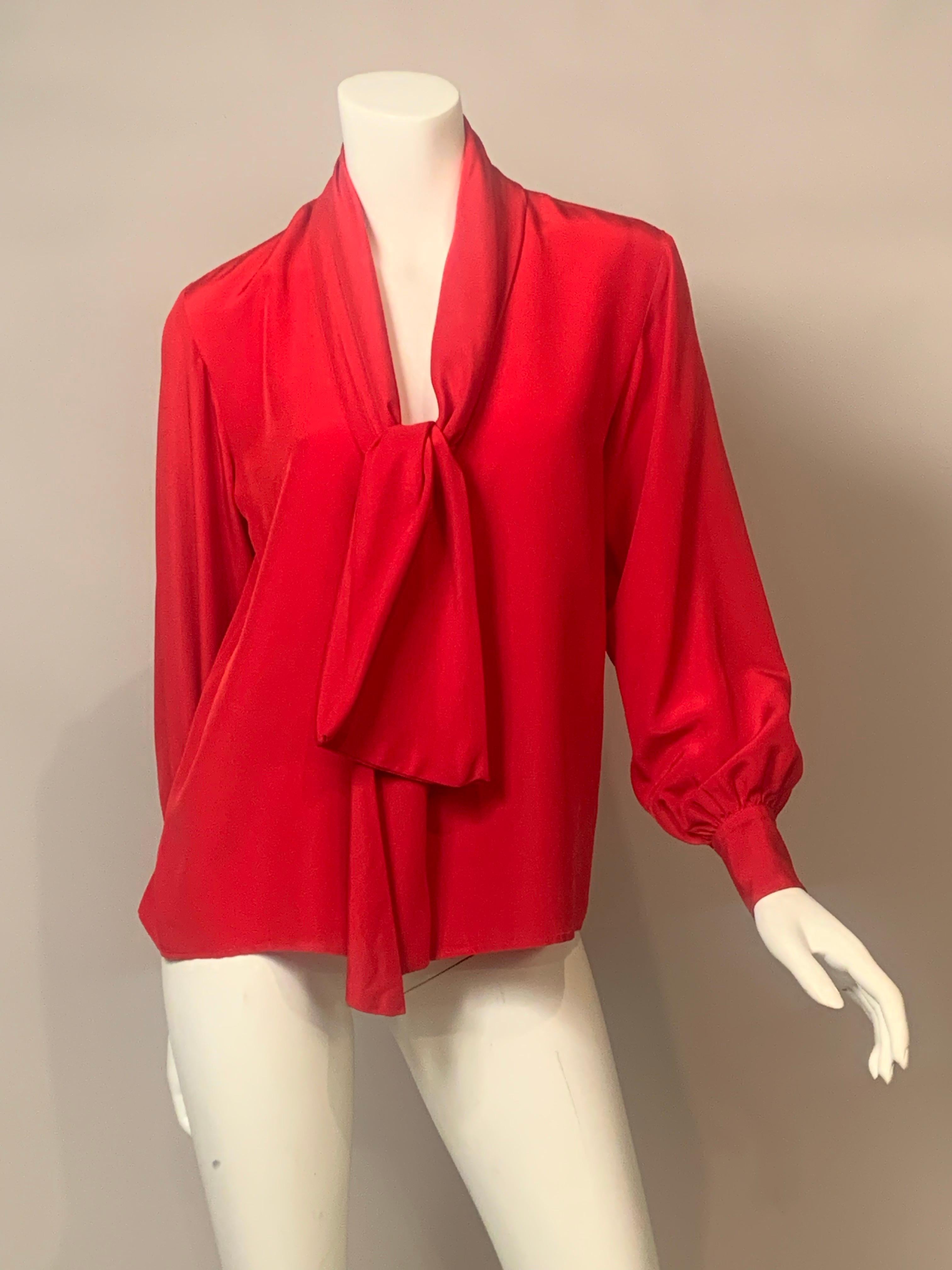 Yves Saint Laurent ha disegnato molte varianti della sua camicetta di seta con scollo a sciarpa o a cravatta.  Questa versione presenta un lungo foulard attaccato su entrambi i lati di una scollatura a V.  In questo caso il lato destro più corto si