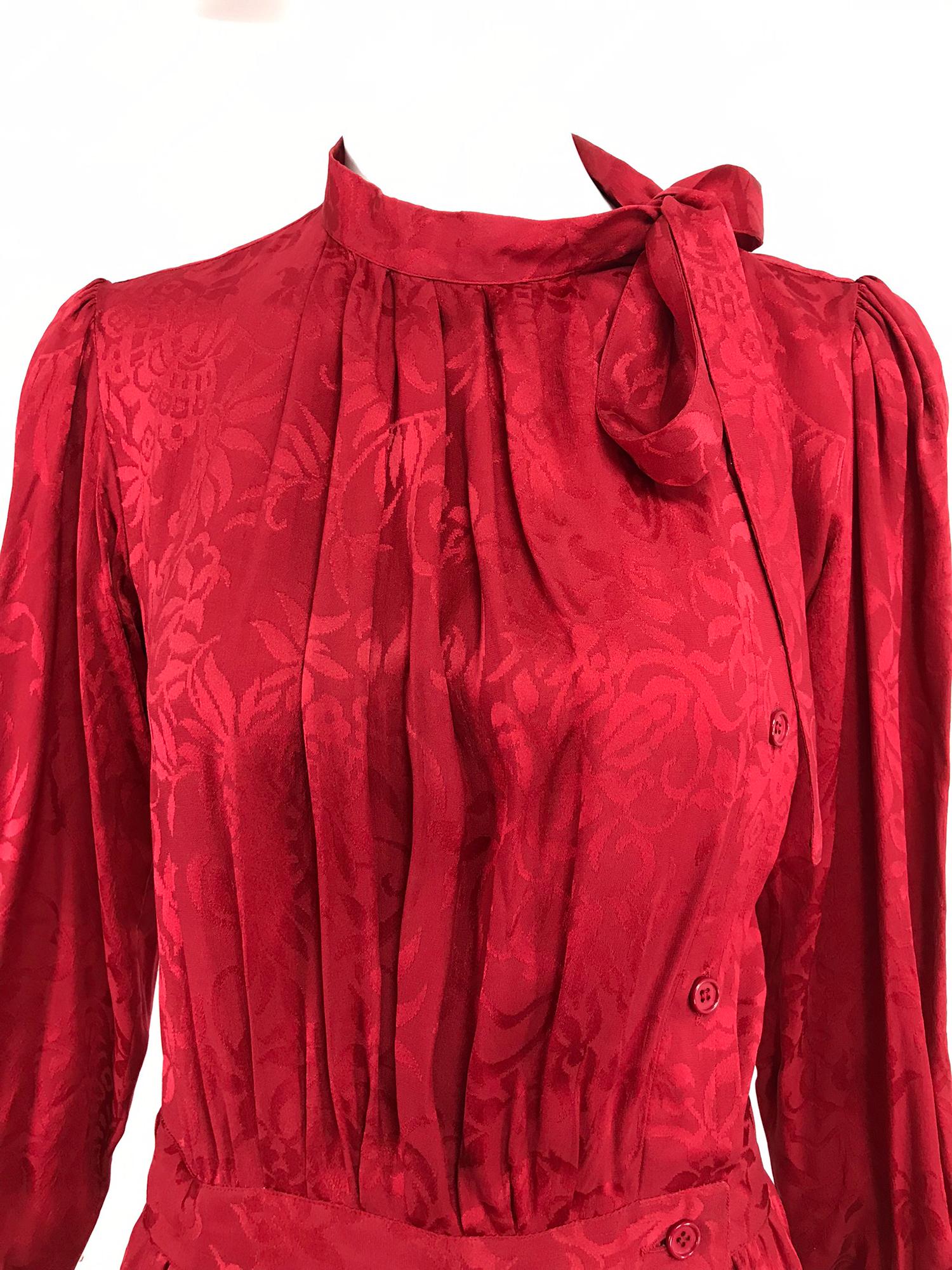 Yves Saint Laurent red silk jacquard bow tie dress from the  1970s. Candy apple red floral figured silk dress features long semi full sleeves with button cuffs, the bodice has a band neckline with ties and closes at the side front with buttons it is