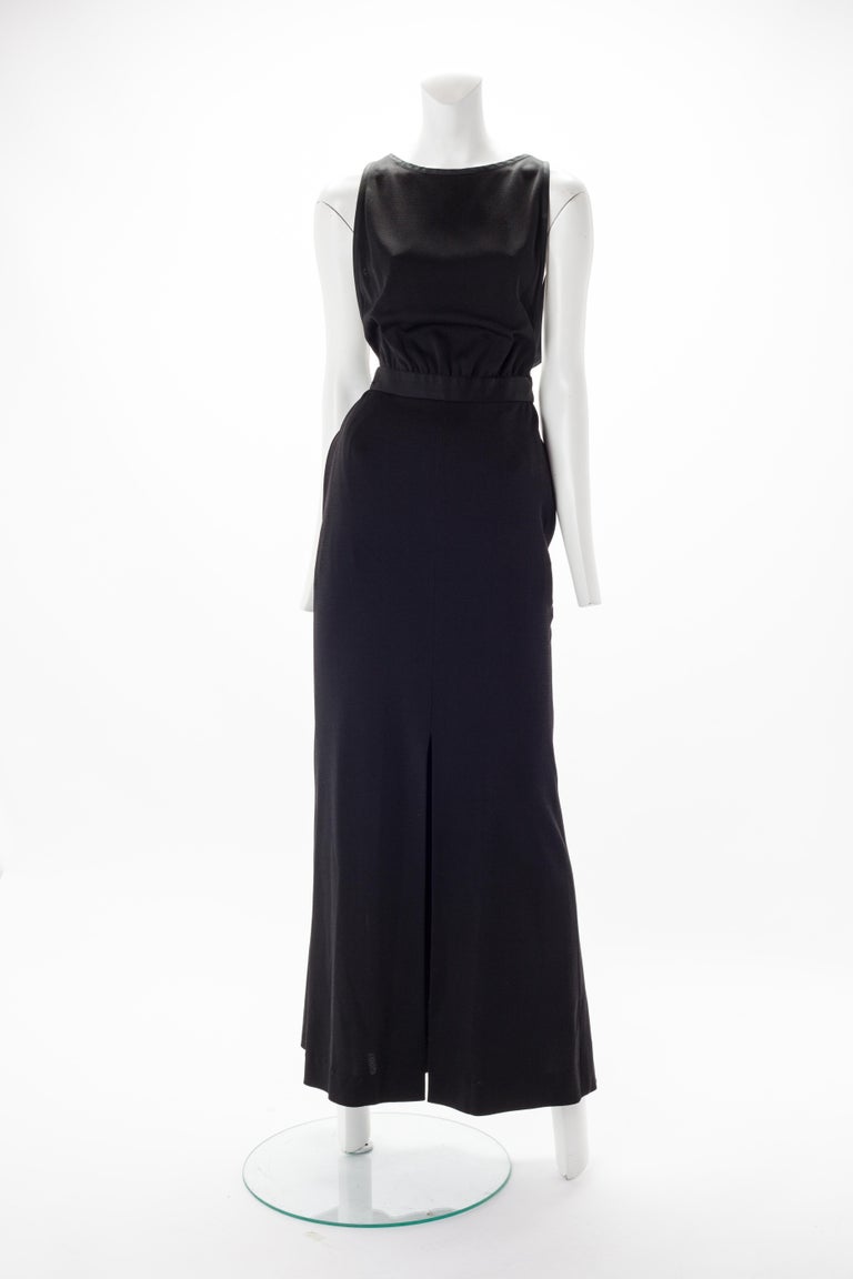 Yves Saint Laurent Rive Gauche Black Gown with Open Back, 1990.
 Full length woven dress with waistband. Features slit at center front and open back with button closure at neck. Hidden side zip and hook and eye closure at waist.
Fits US size 2 to 4. 