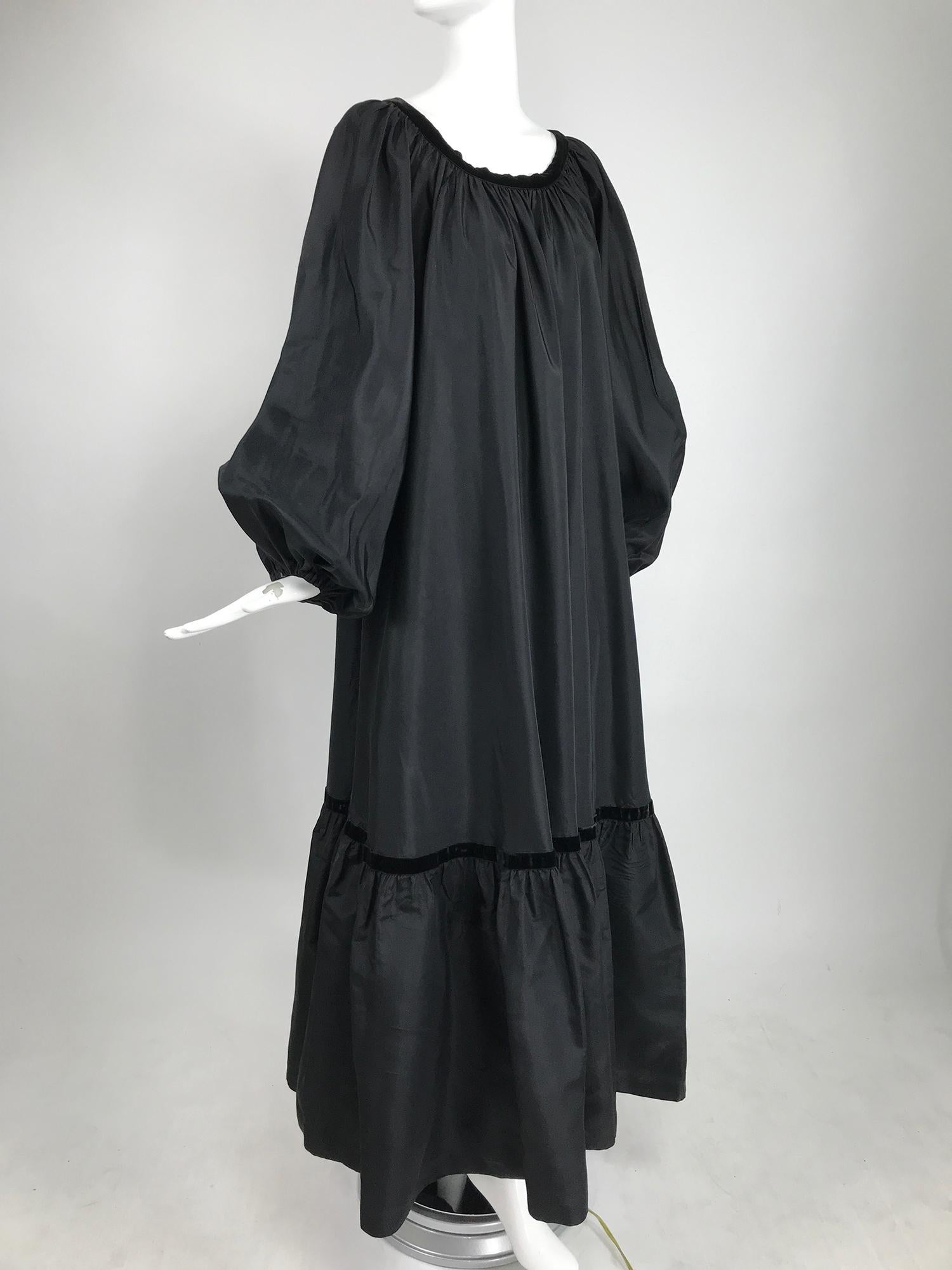 Yves Saint Laurent Rive Gauche black silk taffeta gown from the 1970s. Gypsy/peasant style gown has a open neckline, long very full raglan sleeves have cased elastic cuffs. The dress is gathered at the neck line and falls full to a deep ruffle hem.