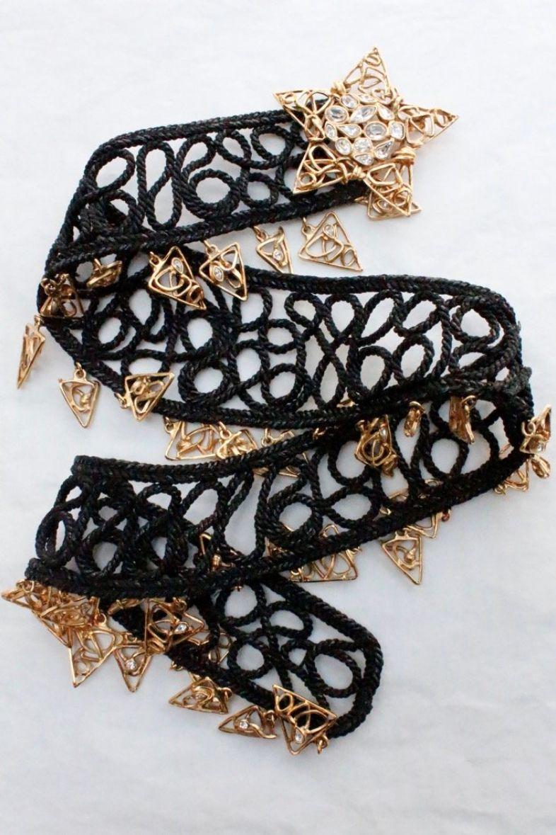 Yves Saint Laurent Rive Gauche (Made in France) Black woven passementerie belt embellished with gilded metal and rhinestones elements. It fastens with a star-shaped buckle. Signed at the back.

Additional information: 
Dimensions: Length: 85 cm