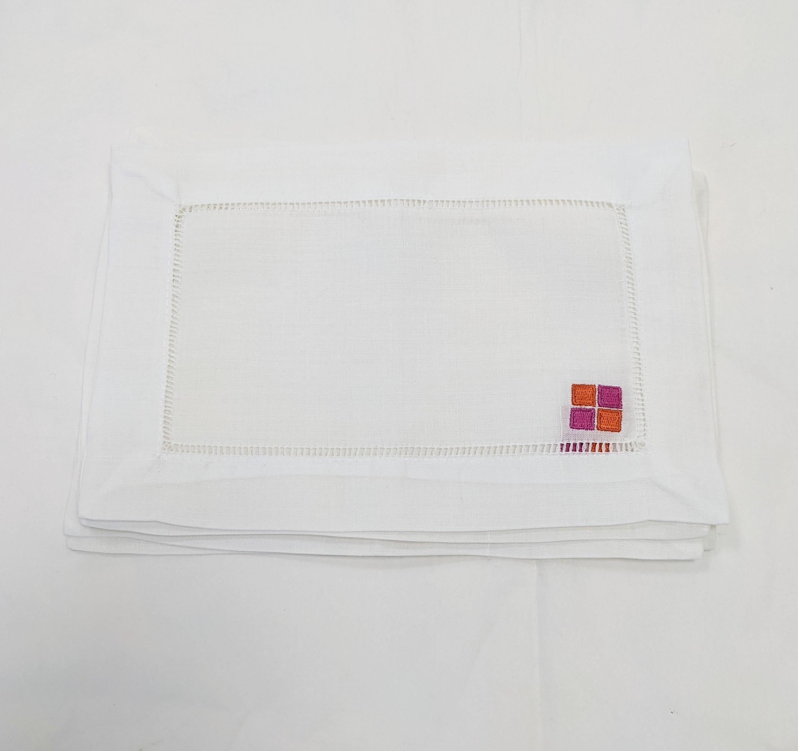  For the YSL collector and lover, an unusual set of six Yves Saint Laurent Rive Gauche cocktail napkins. Of crisp white linen with folded and hemstitched borders, embroidered with the Rive Gauche logo of four signature fuschia pink and orange