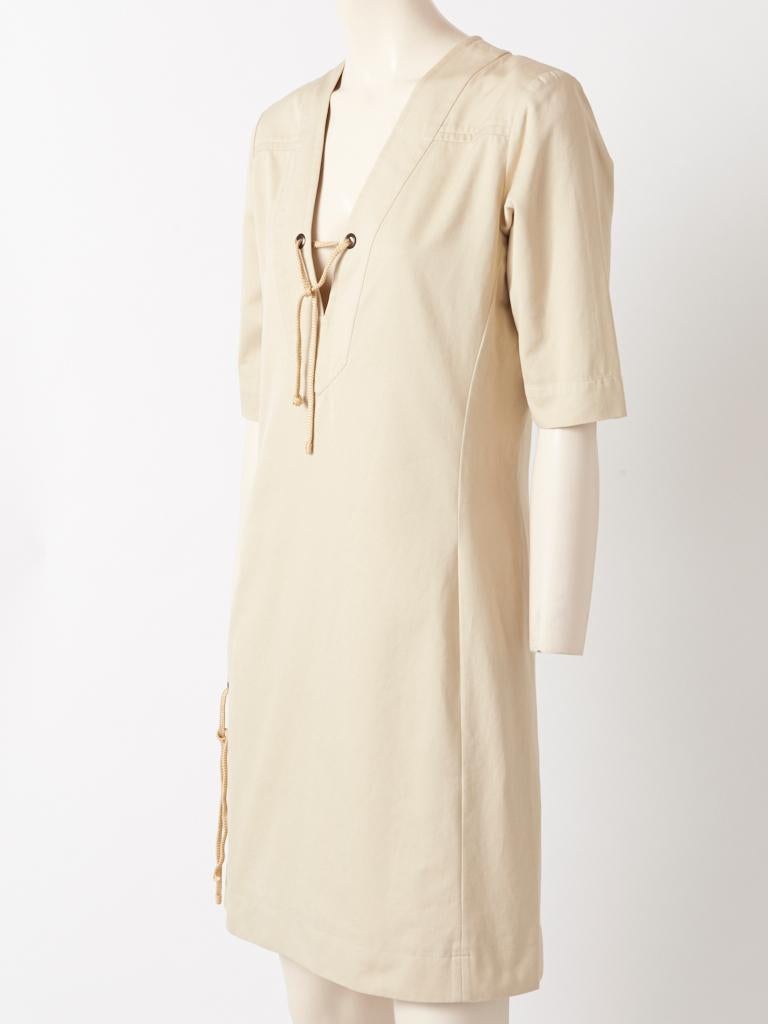 Yves Saint Laurent, Rive Gauche, pale khaki, cotton twill, safari style dress from 1991, having a v neckllne, 3/4 sleeves and deep side slits. Lacing details are at the neckline and sides, Hidden side zippers allow for easy access into the dress.