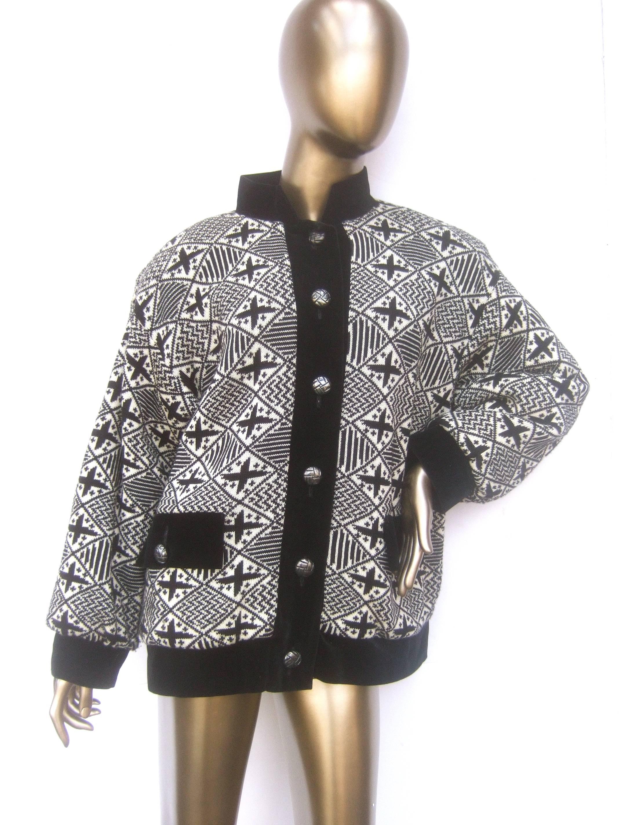 Yves Saint Laurent Rive Gauche geometric wool knit jacket c. 1970s 
The boxy chunky wool knit jacket is designed with a geometric pattern
of black and contrasting white knit. Framed with black velvet border   
trim and matching black velvet nehru