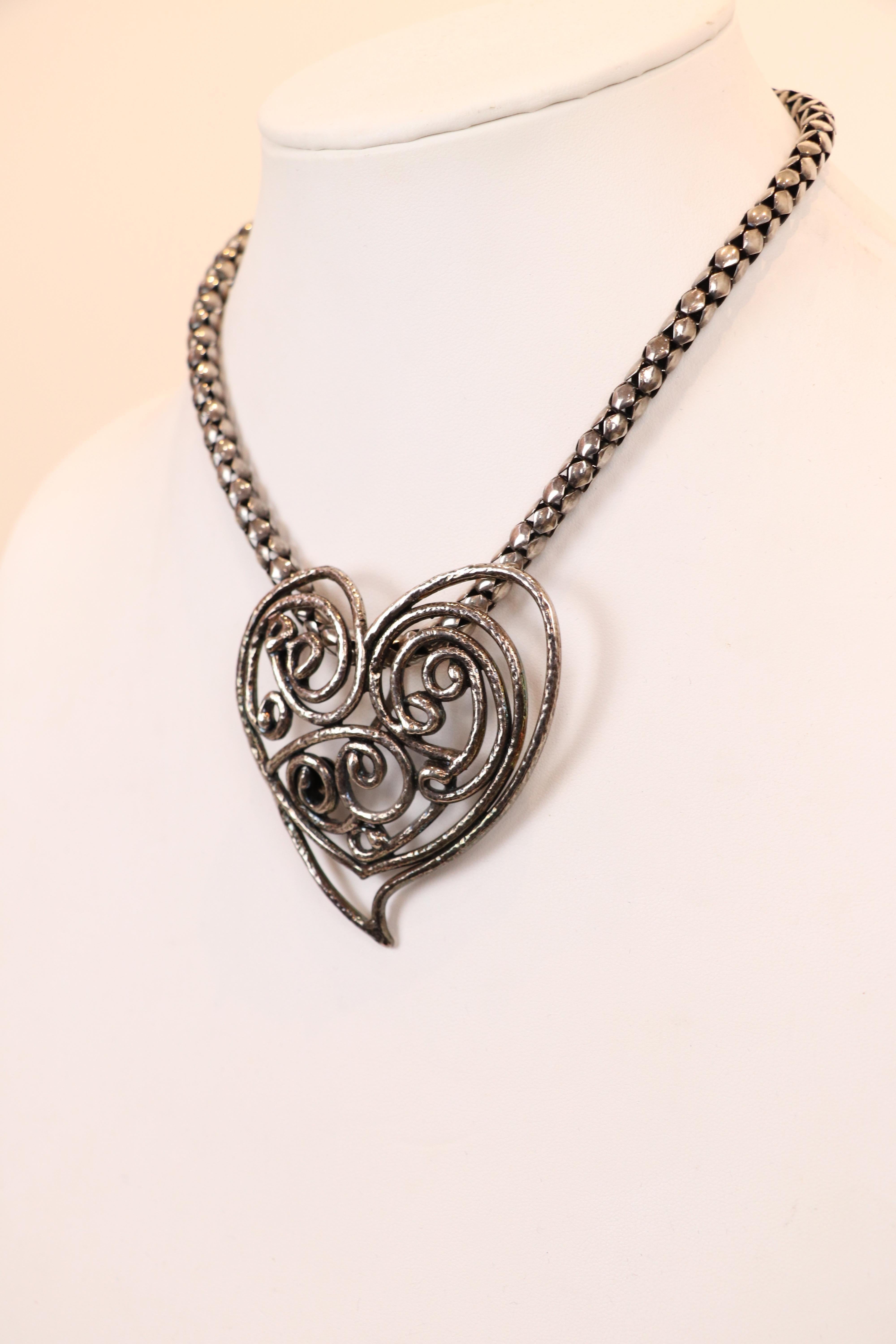 Le collier ras du cou vintage Yves Saint Laurent Rive Gauche des années 1980 comprend un pendentif en forme de cœur massif en argent sur une chaîne serpent en argent avec un fermoir à crochets. Le métal présente une patine vieillie et un motif