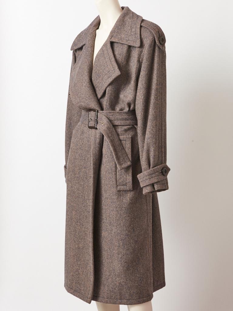 Yves Saint Laurent, Rive Gauche, belted, herringbone pattern, wool coat, having oversized wide lapels, shoulder epaulettes, and top stitching detail along the collar.
Oversized , menswear silhouette.