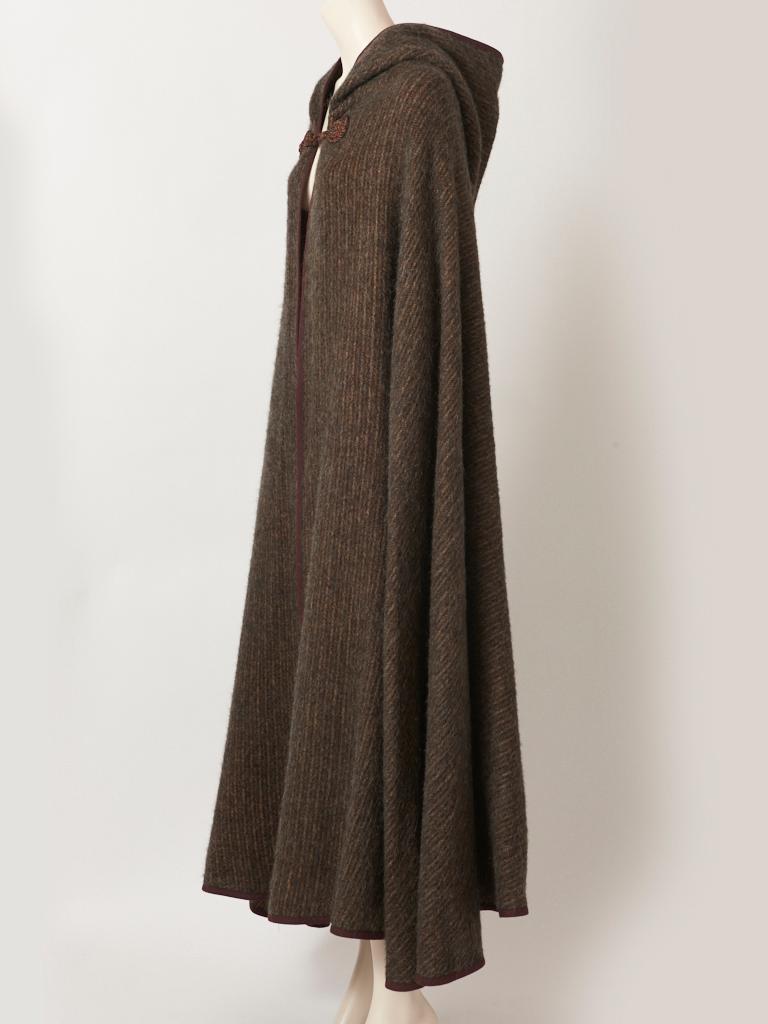  Yves Saint Laurent, Rive Gauche, wool and mohair, Moroccan inspired 1970's cape with an attached hood. This cape is made of 30% mohair and 70% wool. It is a dark grayish color, having  subtle earth tone stripes in beige and brown. The cape has a