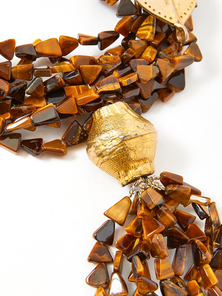 Yves Saint Laurent, tiger's eye quartz beaded, multi strand, African inspired necklace with a tassel pendent detail, attached with a textured gold tone bead. The clasp is a also a gold tone, sculpted butterfly. Necklace is adorned with gold abstract