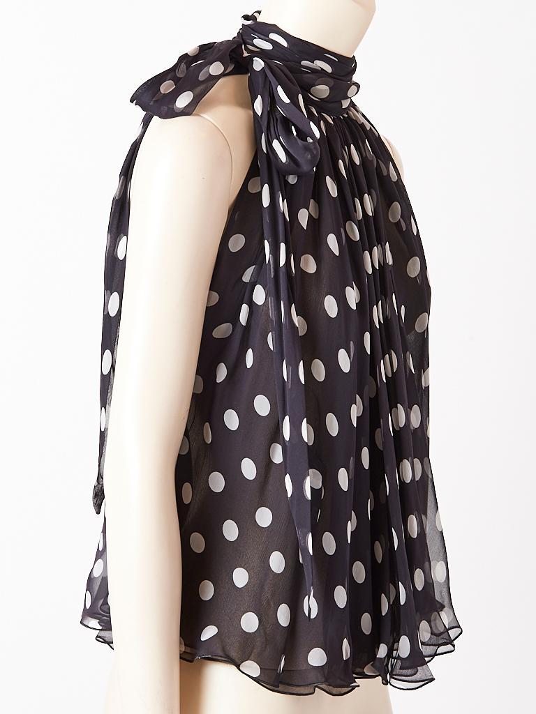 Yves Saint Laurent, Rive Gauche, navy and white polka dot, chiffon, lavaliere blouse having a bias cut loose fitting body and halter cut armholes. Blouse has multi layers of chiffon and flows against the body.