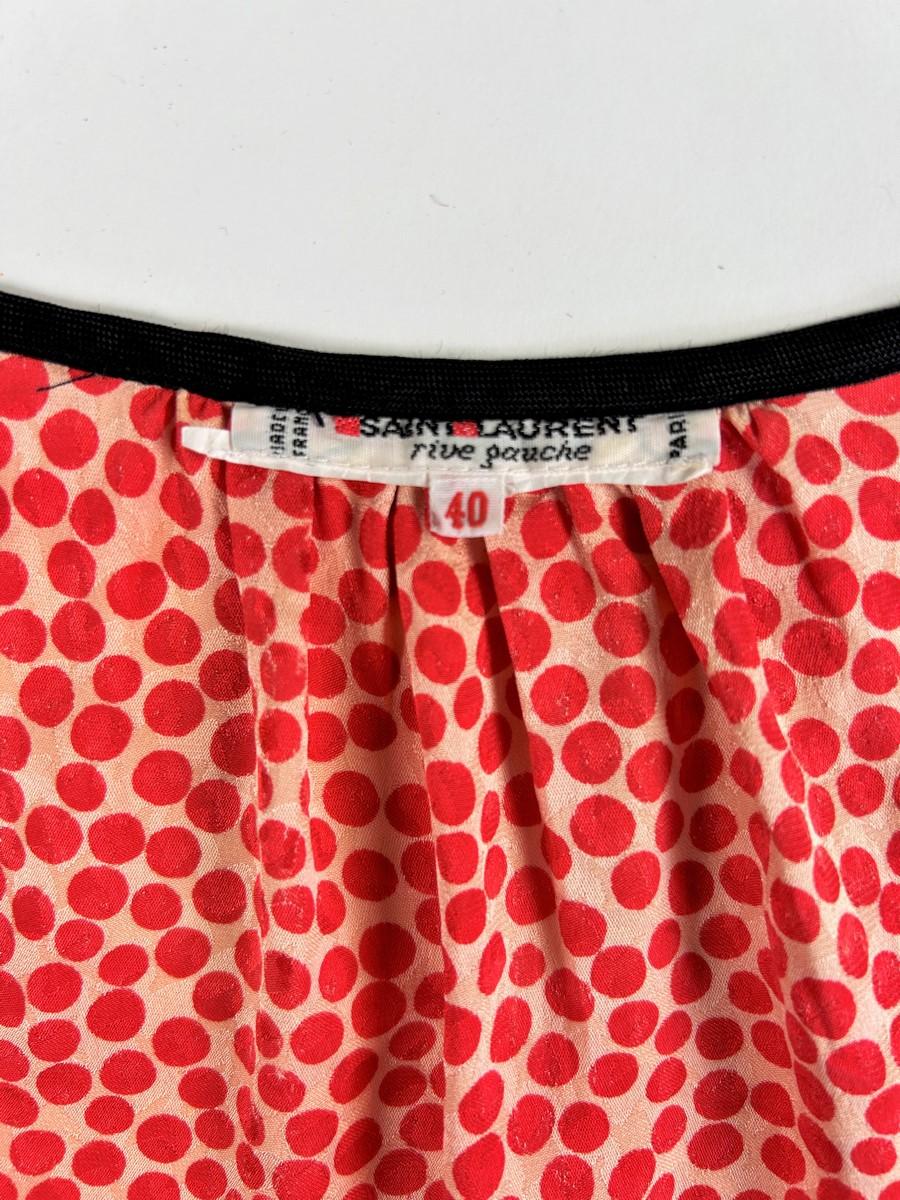 Circa 1976. Francia
Iconica blusa Russ in pongee di seta damascata stampata a pois rossi di Yves Saint Laurent Rive Gauche, risalente agli anni chiave della collezione Opéra Ballets Russes. Camicetta ampia, maniche lunghe con piccoli sbuffi stretti