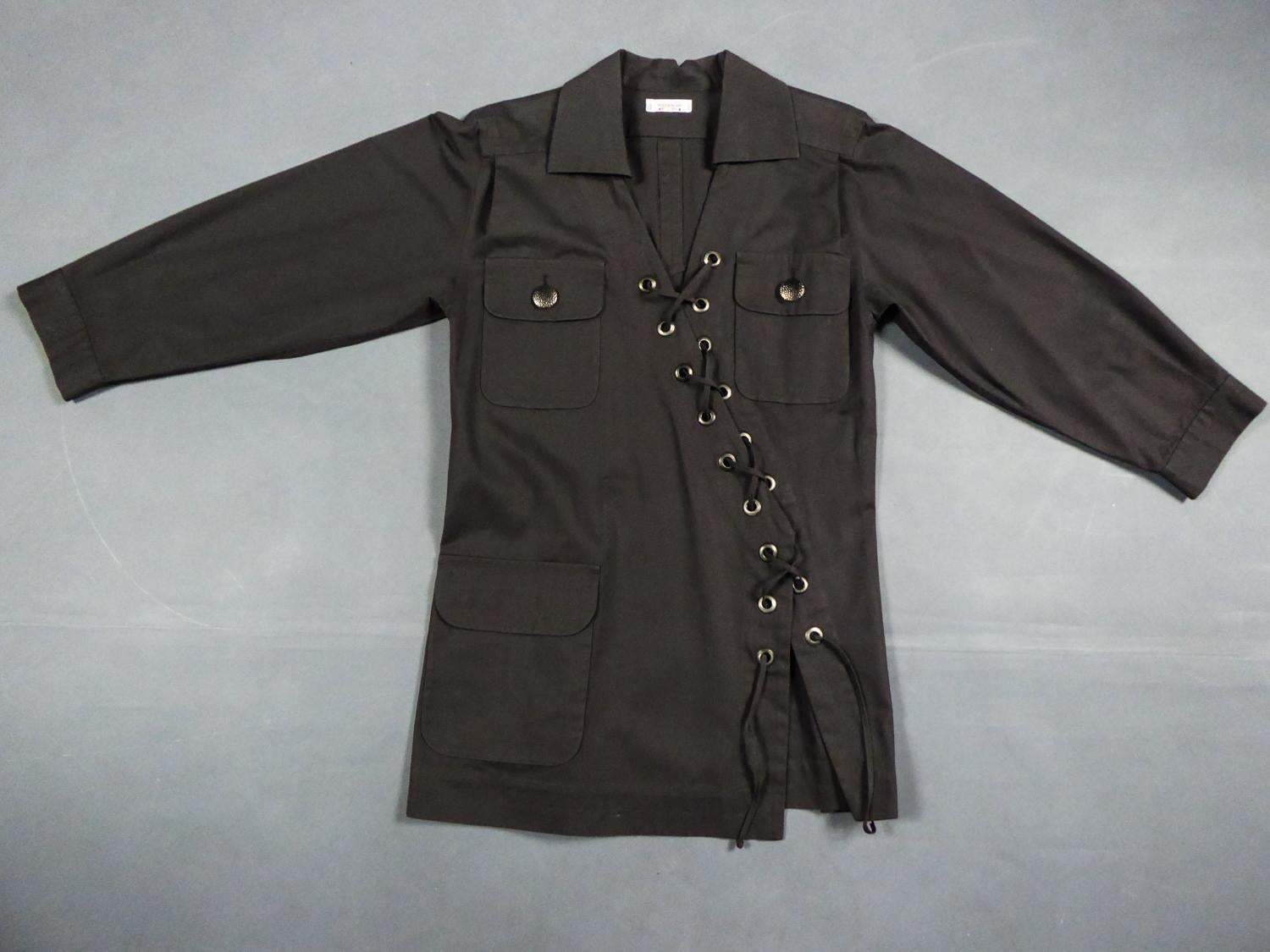 Ca. 1995/2000. Frankreich
Ikonische Yves Saint Laurent Rive Gauche Bluse aus schokoladenbraunem Baumwoll-Gabardine aus den späten 1990er Jahren. Andere Version der Saharan von 1969 mit dieser asymmetrischen Nietenschnürung, die nur drei echte