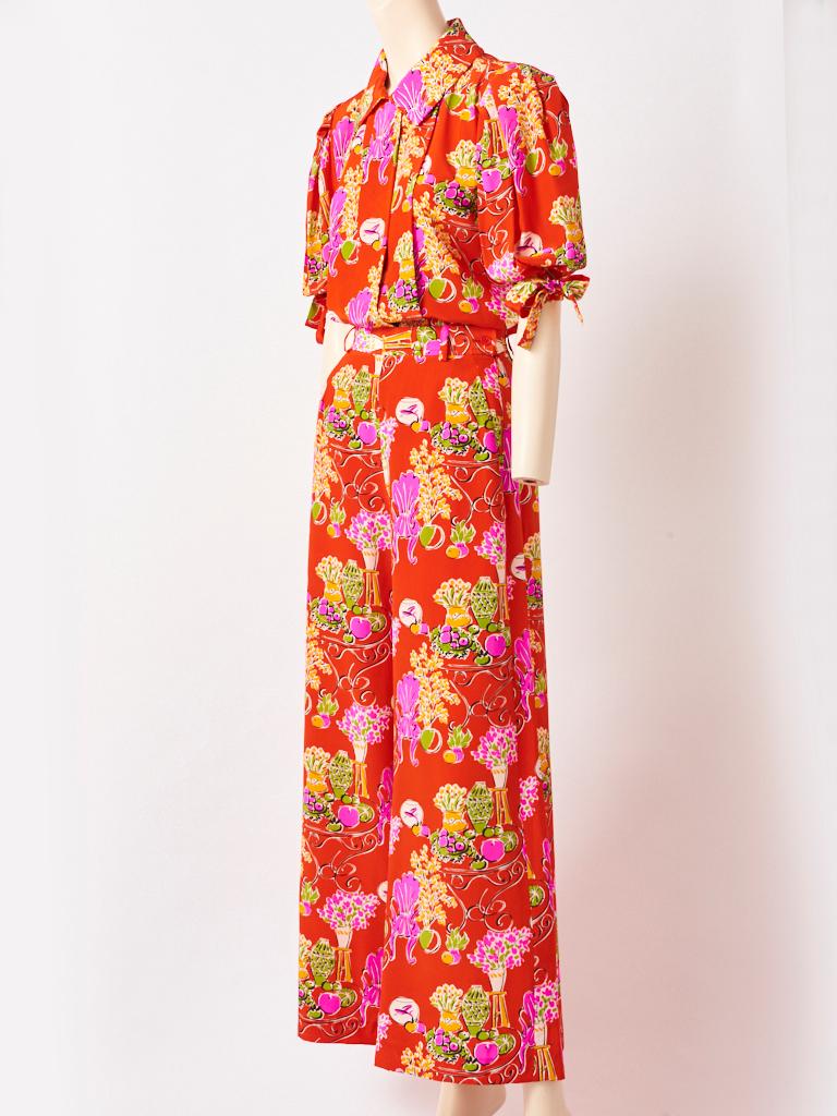 Yves Saint Laurent, Rive Gauche, silk two piece top and pant pajama ensemble, having a red ground 
with a multi tone abstract floral pattern throughout. Blouse has full sleeves that end at the elbow having ties and a semi pouf at the shoulders. The