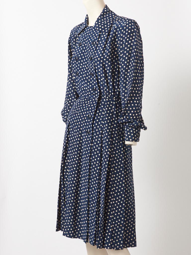 Yves Saint Laurent, Rive Gauche, long sleeve, navy and white polka dot, silk day dress, having a pointed collar, double breasted closures at the bodice, and a box bleated skirt. C. 1980's.