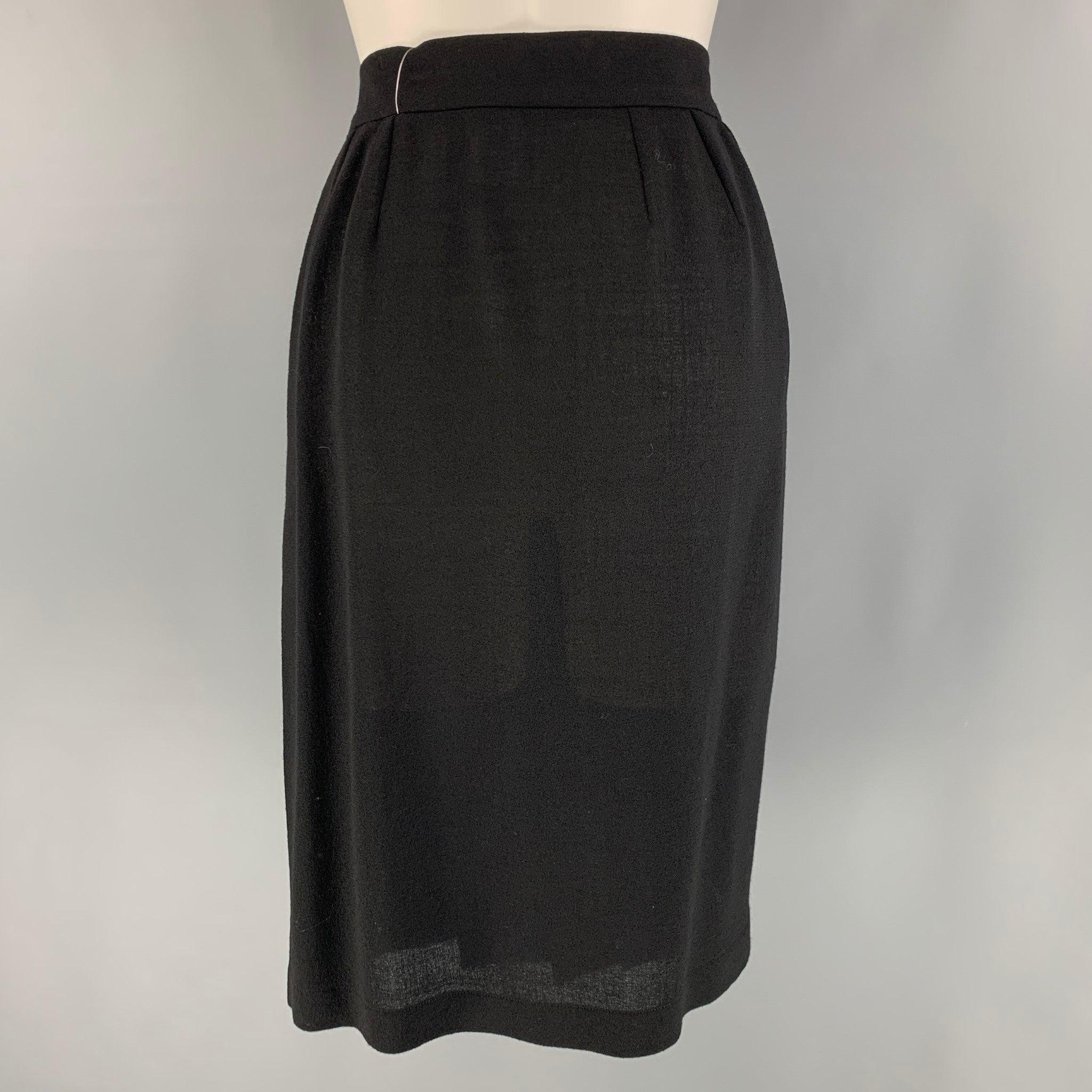 YVES SAINT LAURENT 'Rive Gauche' knee high skirt comes in a black wool material featuring a wrap style, front drape and pleated detail, and hook closure. Made in France.Very Good Pre-Owned Condition. 

Marked:   38 

Measurements: 
  Waist: 28