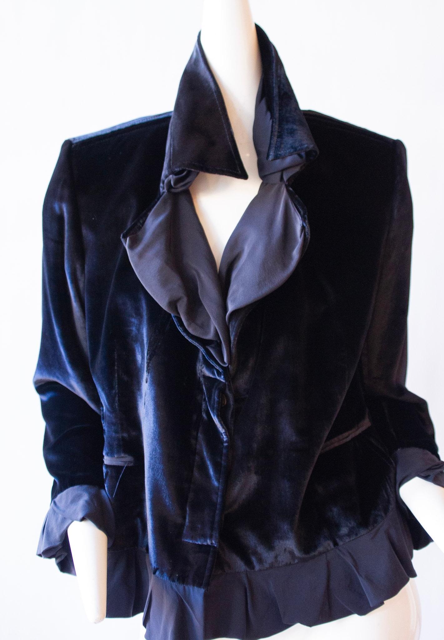 This luxurious velvet jacket is crafted by the renowned Yves Saint Laurent. With an exquisite ruffle collar, cuffs and hem, it offers an aristocratic finish. The jacket is 21