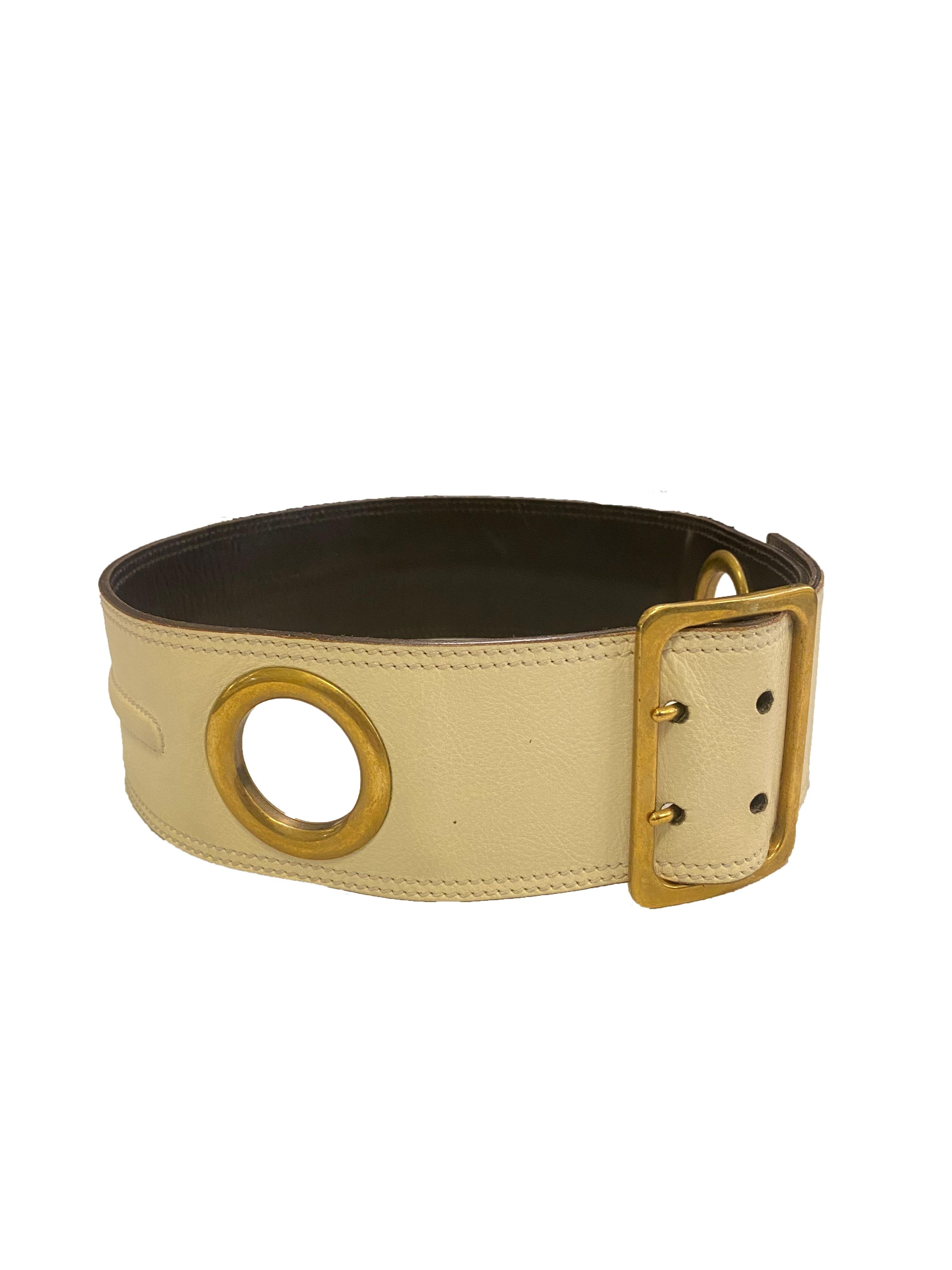 Vintage leather belt from Yves Saint Laurent Rive Gauche. Made in Italy, 1980's. Wide belt in deep cream caviar leather with oversized brassy gold toned metal eyelets. Fixed with a large double pronged buckle fastening branded 'YSL' on the