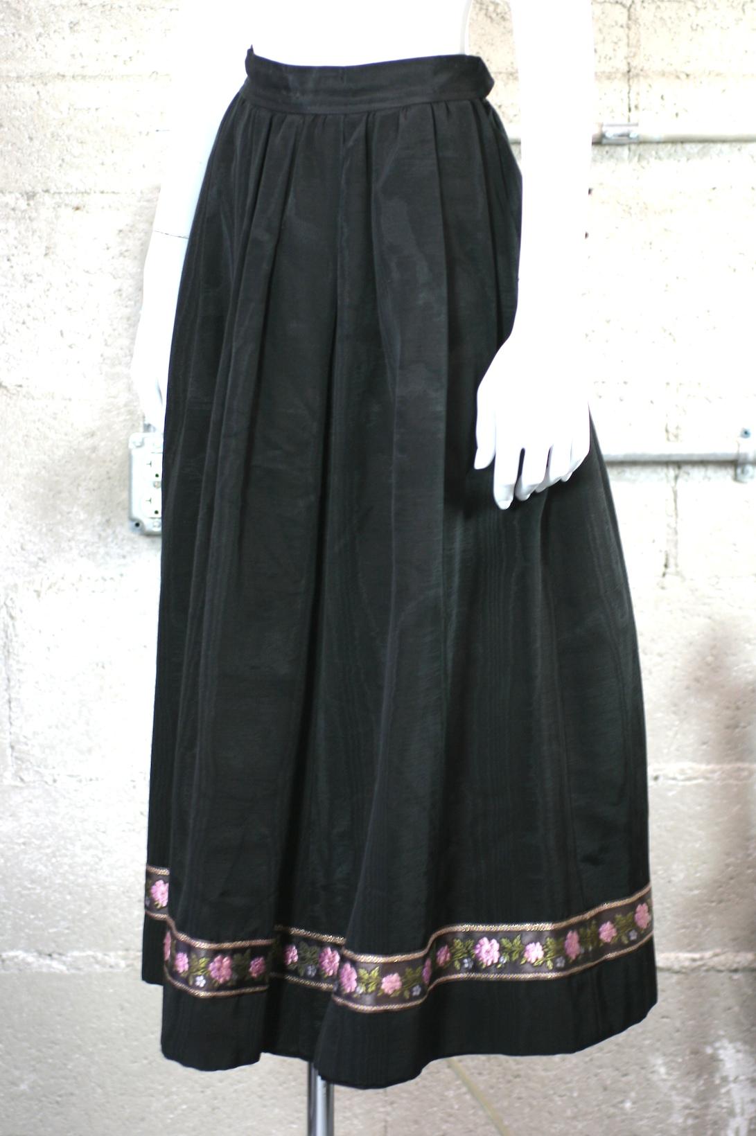 Yves Saint Laurent moire taffeta skirt with floral tapestry ribbon trim. Simple construction with gathered waist falling to full skirt. 
YSL Russian Collection. Side zip closure with 2 pockets. 1970's France.
Vintage size 38,   
Waist 24