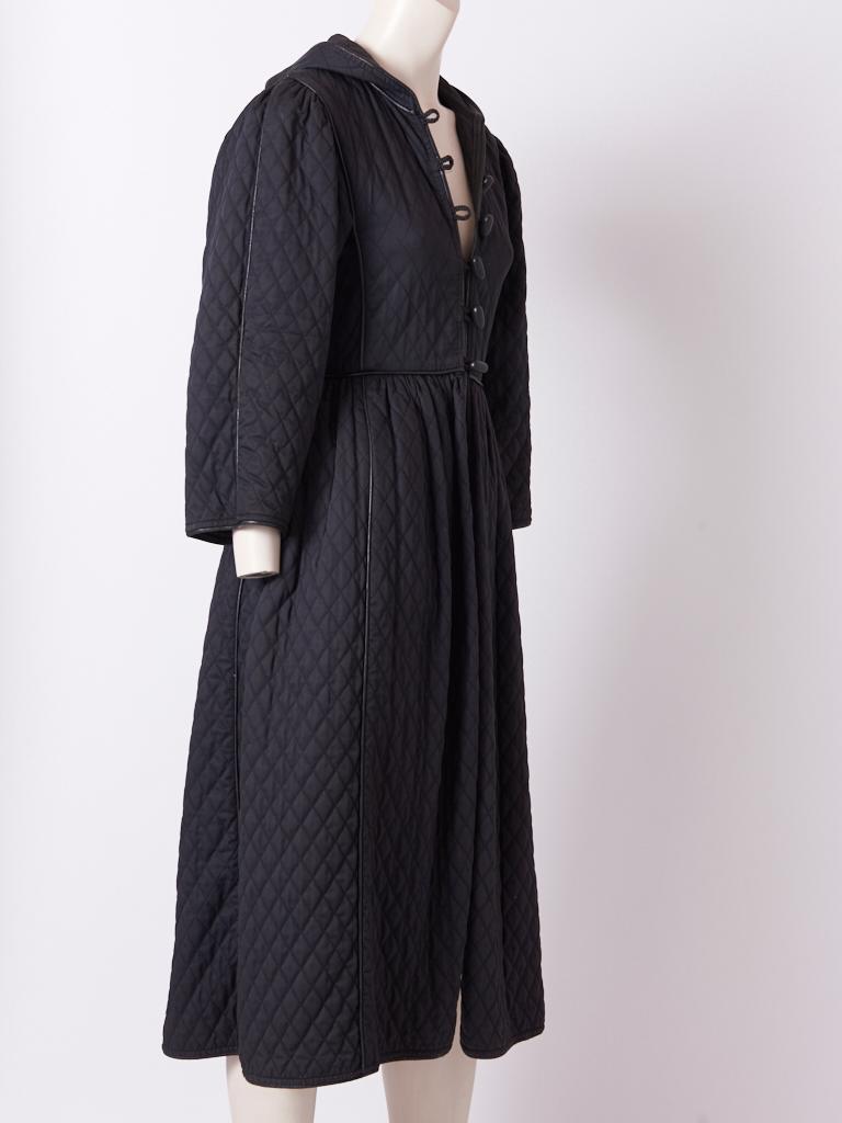 Yves Saint Laurent, Rive Gauche, iconic, Russian collection, black, quilted cotton coat with an attached hood having leather piping detail and black wood toggle button closures. C. 1975-76.  