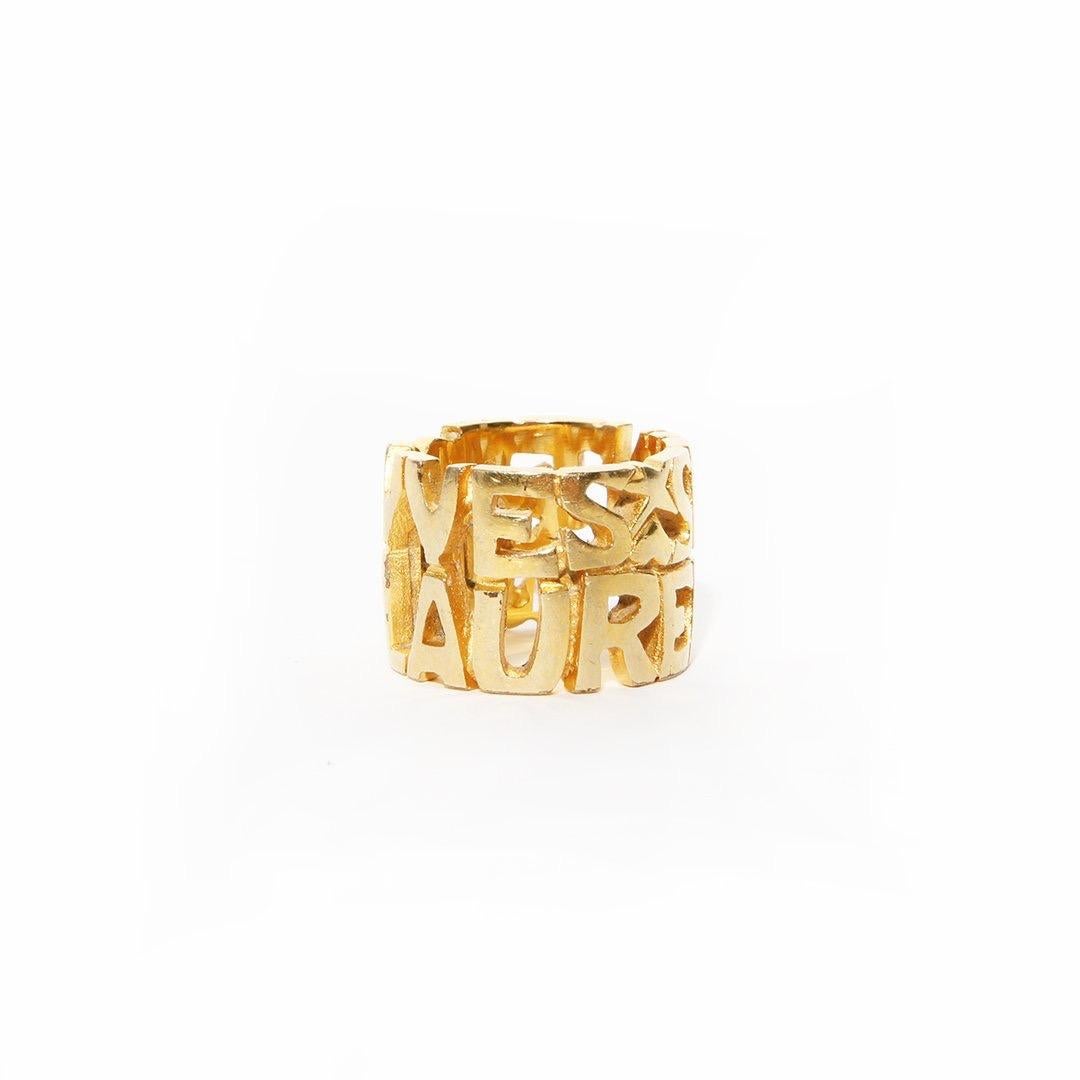 Script ring by Yves Saint Laurent 
Gold-tone hardware 
Cutout logo ring 
Heart and star cutout 
Condition: Great, some scratching and marks on hardware. (see photos) 
Size/Measurements: (approximate) 
Size 6.5
6.5cm 