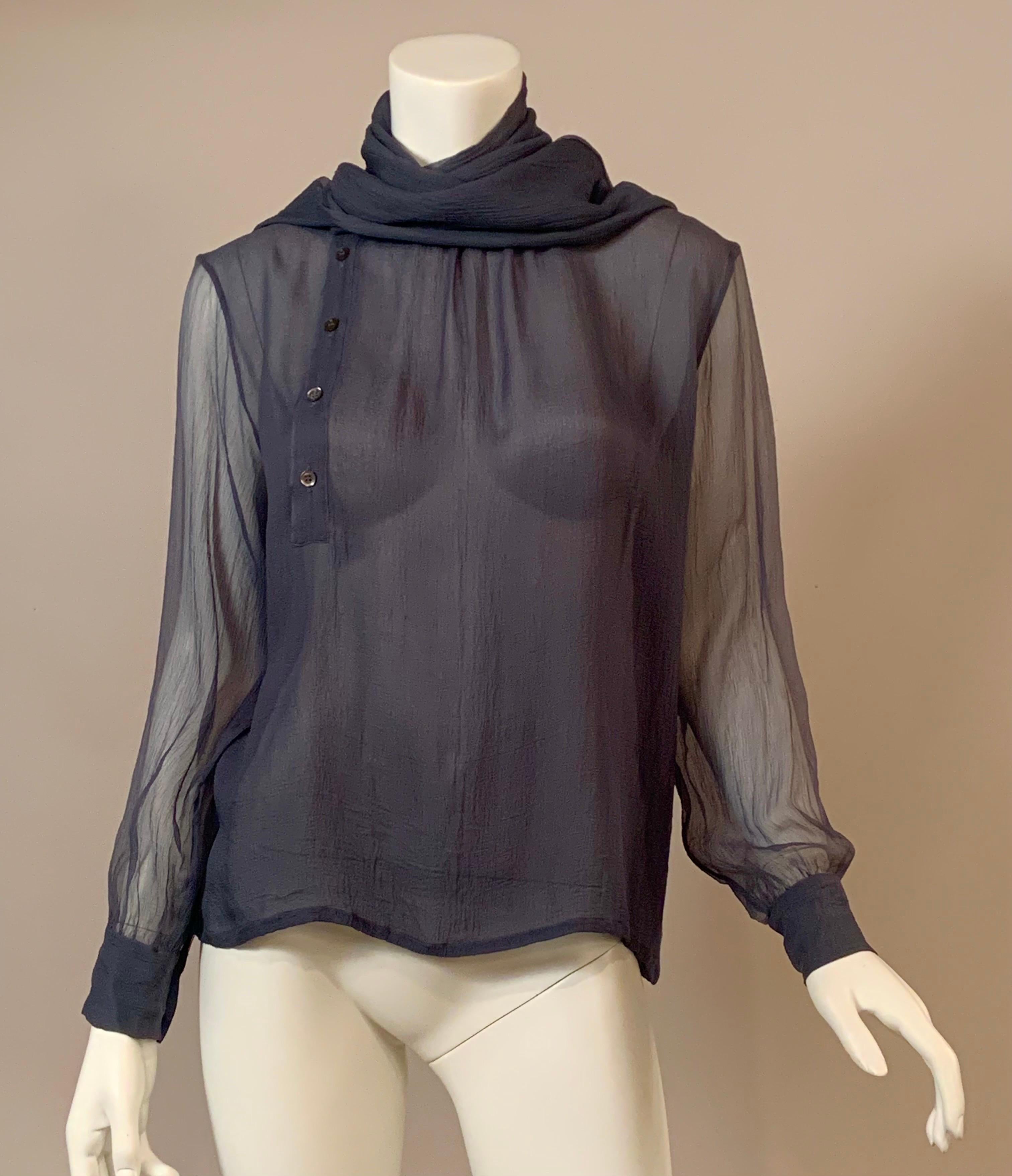 Yves saint Laurent designed this 1970's sheer  slate blue silk georgette blouse with an unusual neckline.  The blouse slips om over your head and buttons half way down the front, and to the right of the center.  This is covered by attached scarf if