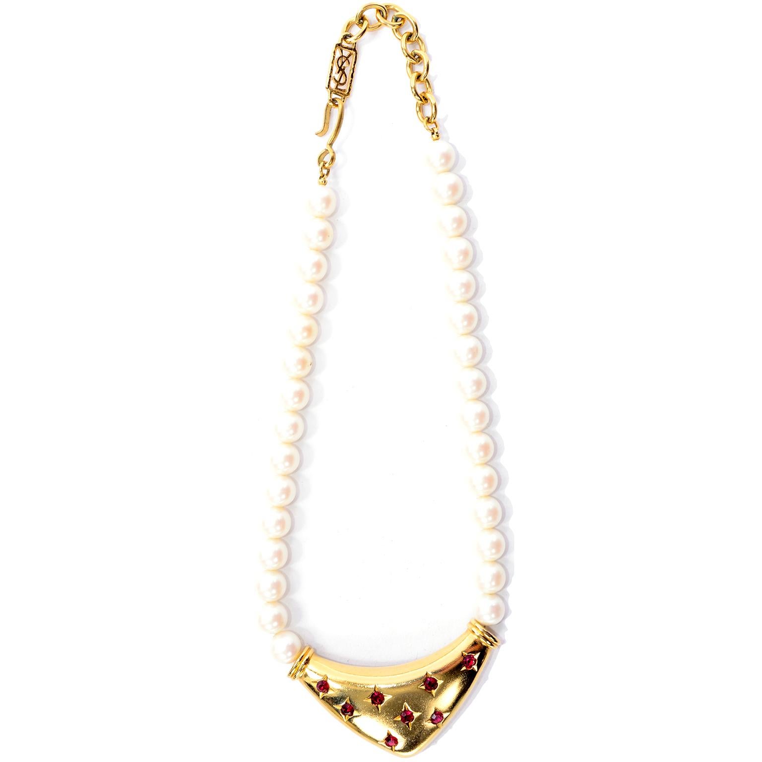 This is a stunning vintage bib necklace from Yves Saint Laurent with a single strand of faux pearls and a gorgeous gold abstract triangle with beautiful red faceted stones that give the appearance of little stars. The necklace has the YSL logo on