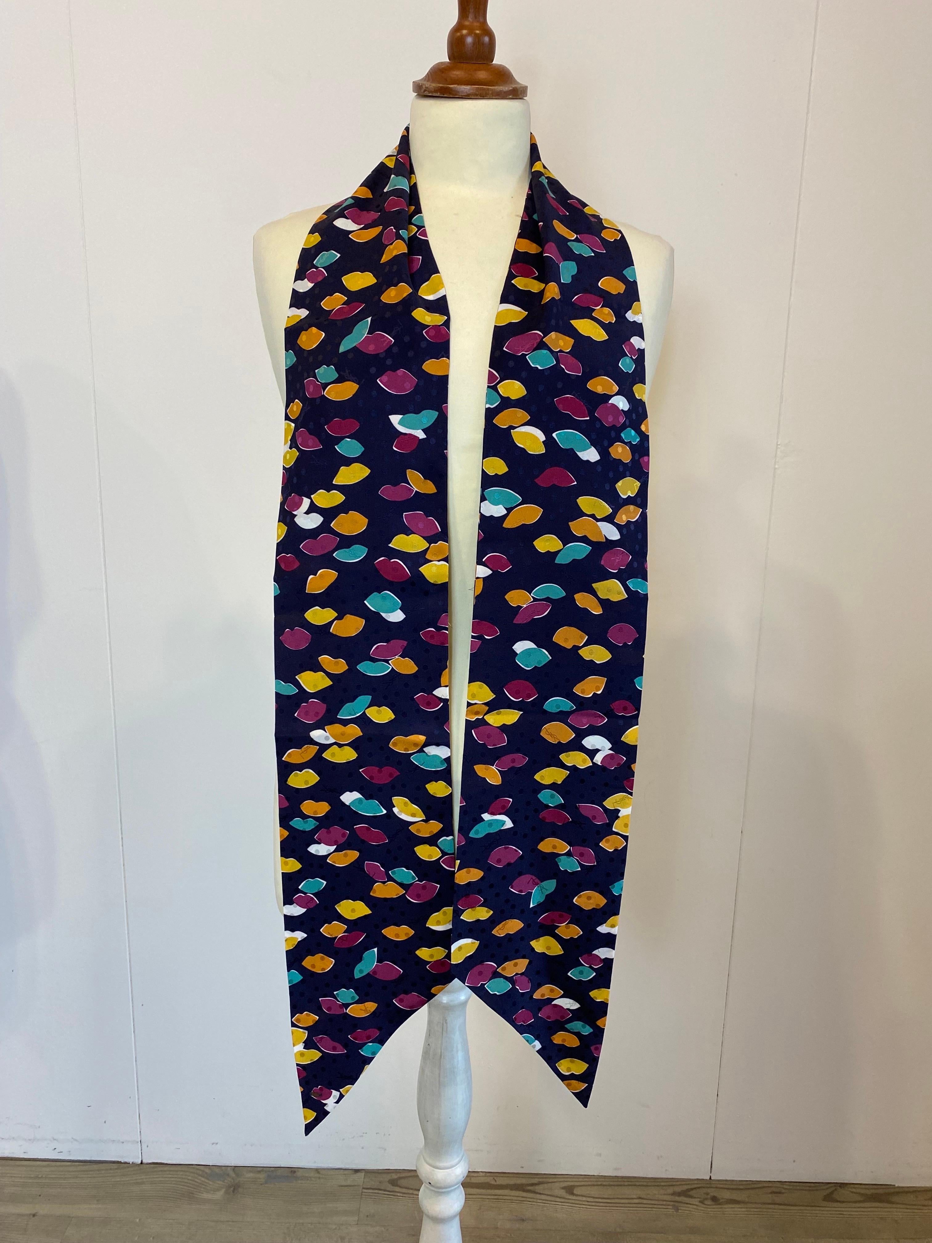 Yves Saint Laurent silk bandolier, blue background with tone-on-tone polka dots and many colored mouth designs.
It is in very good condition.
Length 184 cm
Width 14 cm