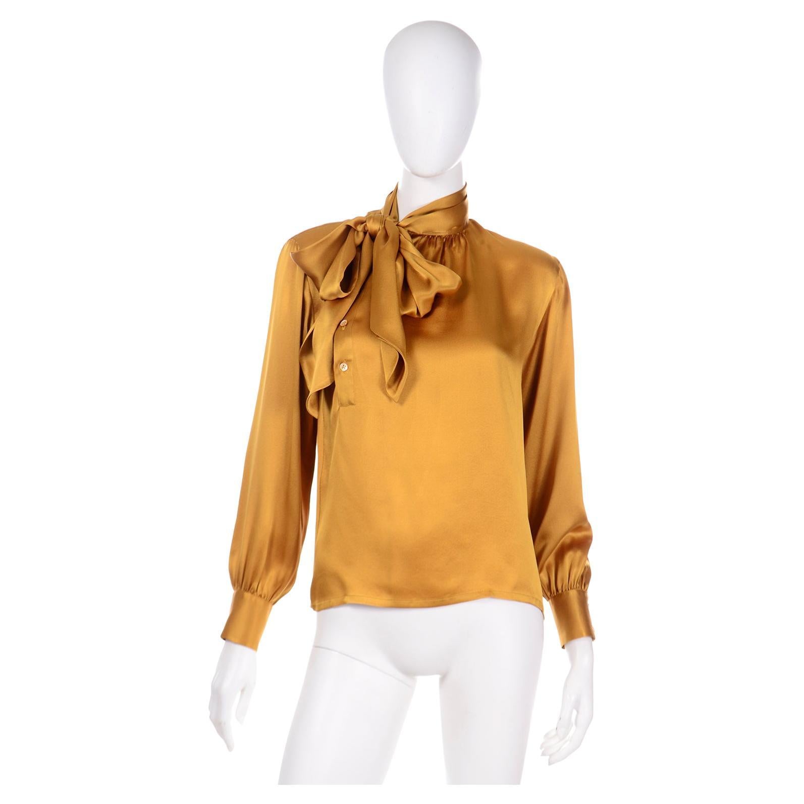 This is a luxurious Yves Saint Laurent gold silk charmeuse vintage blouse from the late 1980's with an attached sash that can be tied into a knot or a bow and a separate sash belt that can be worn around the waist or as a head scarf.

In Yves Saint