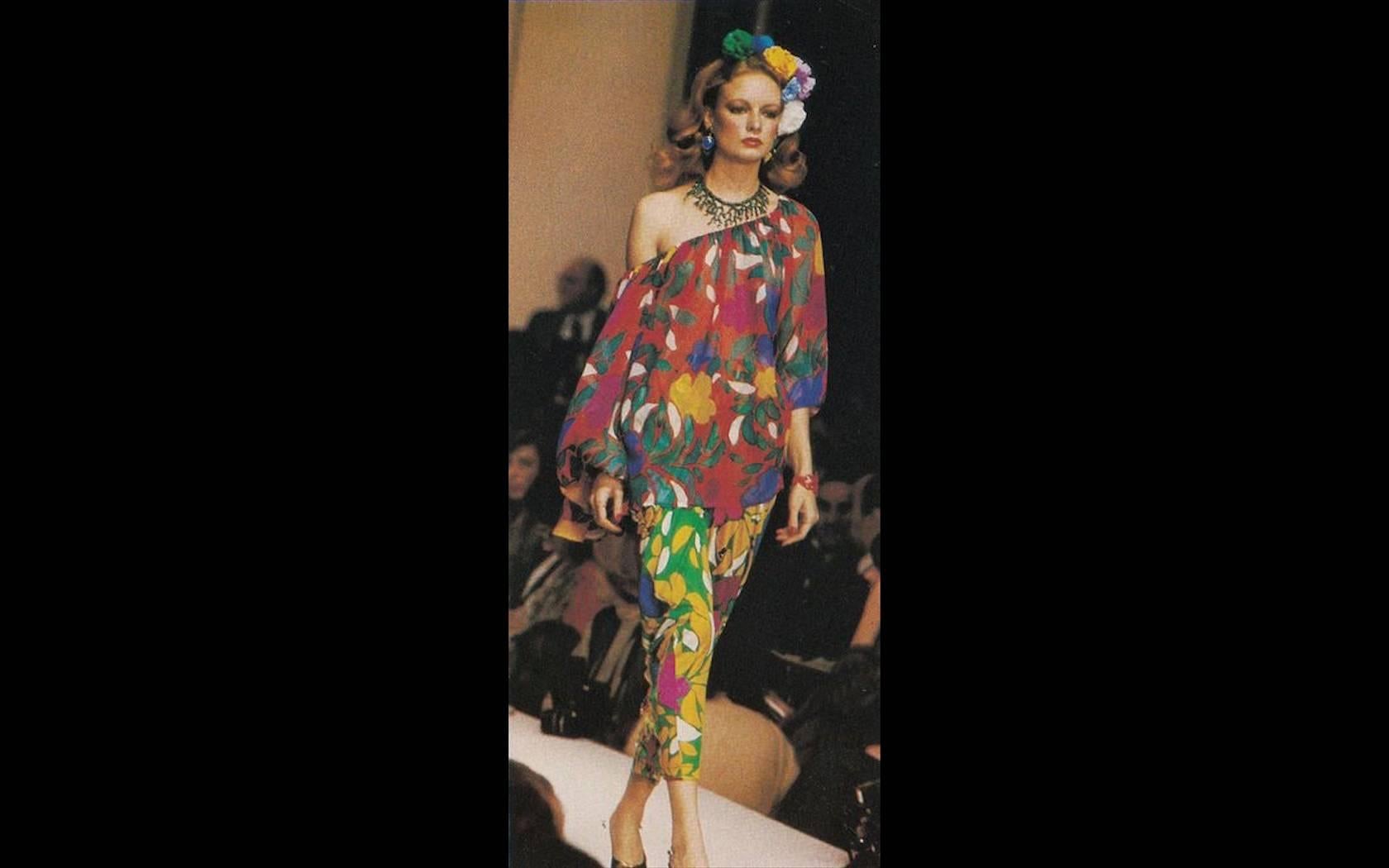 Un imprimé de fleurs tropicales dans des couleurs Pop Art vibrantes fait de cette blouse en mousseline de soie conçue par Yves Saint Laurent une étonnante trouvaille vintage. Faisant partie de sa collection printemps/été 1979, il était positivement