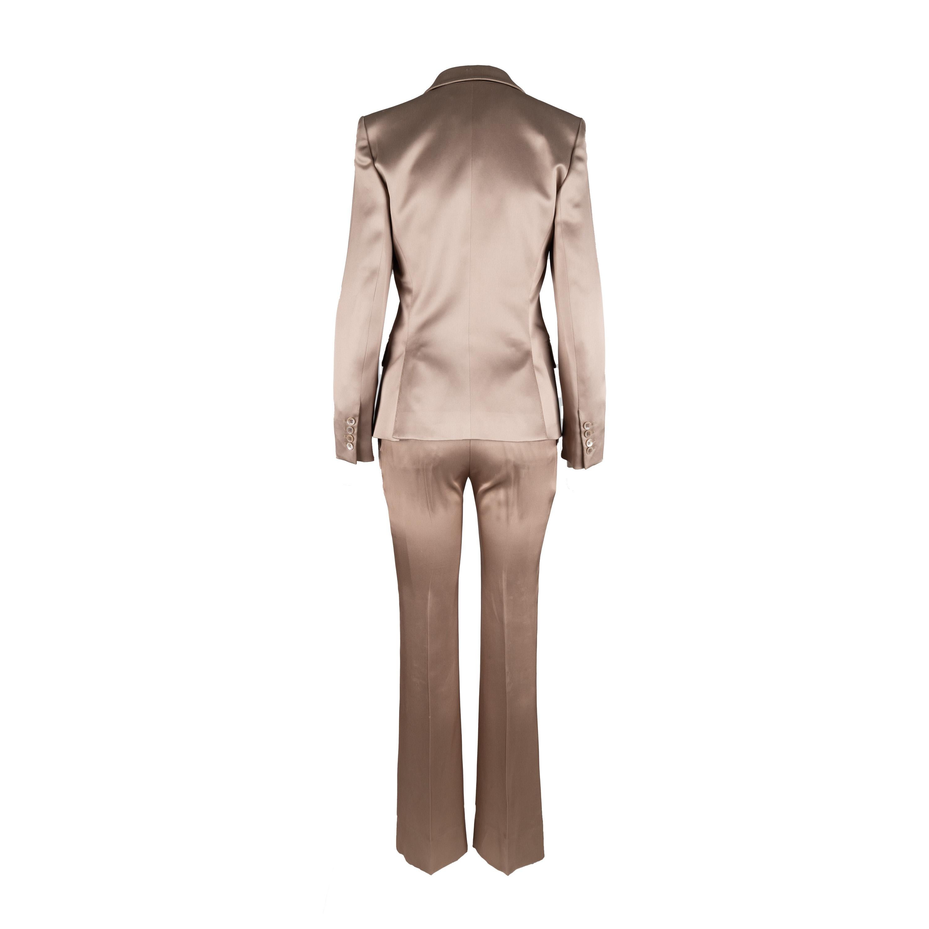 Ce tailleur en soie Yves Saint Laurent, conçu par Tom Ford vers les années 2000, est confectionné de manière experte en 100 % soie dans une teinte beige subtilement brillante. Il est doté d'un col à revers, d'un bouton sur le devant, de deux poches