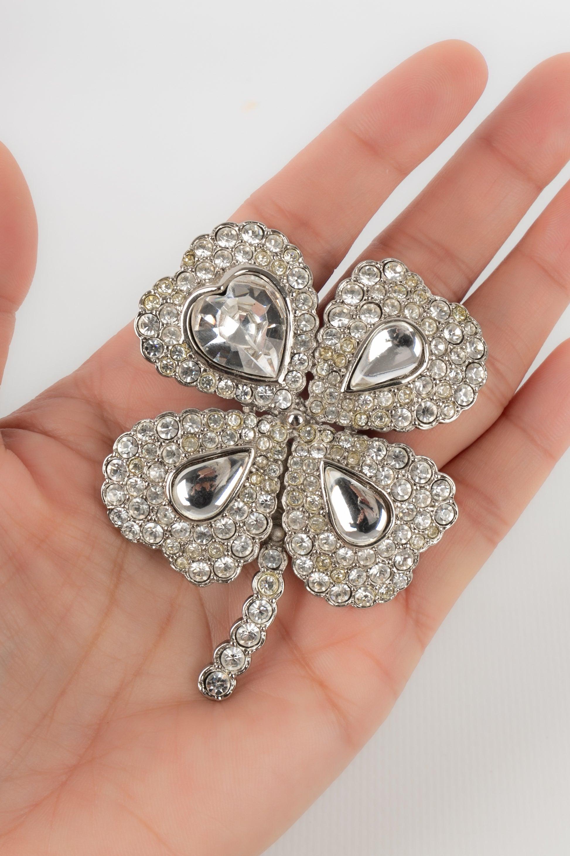 Yves Saint Laurent - (Made in France) Silvery metal pendant brooch ornamented with rhinestones and representing a four-leaf clover.

Additional information:
Condition: Very good condition
Dimensions: 7 cm x 5.5 cm

Seller Reference: BR153