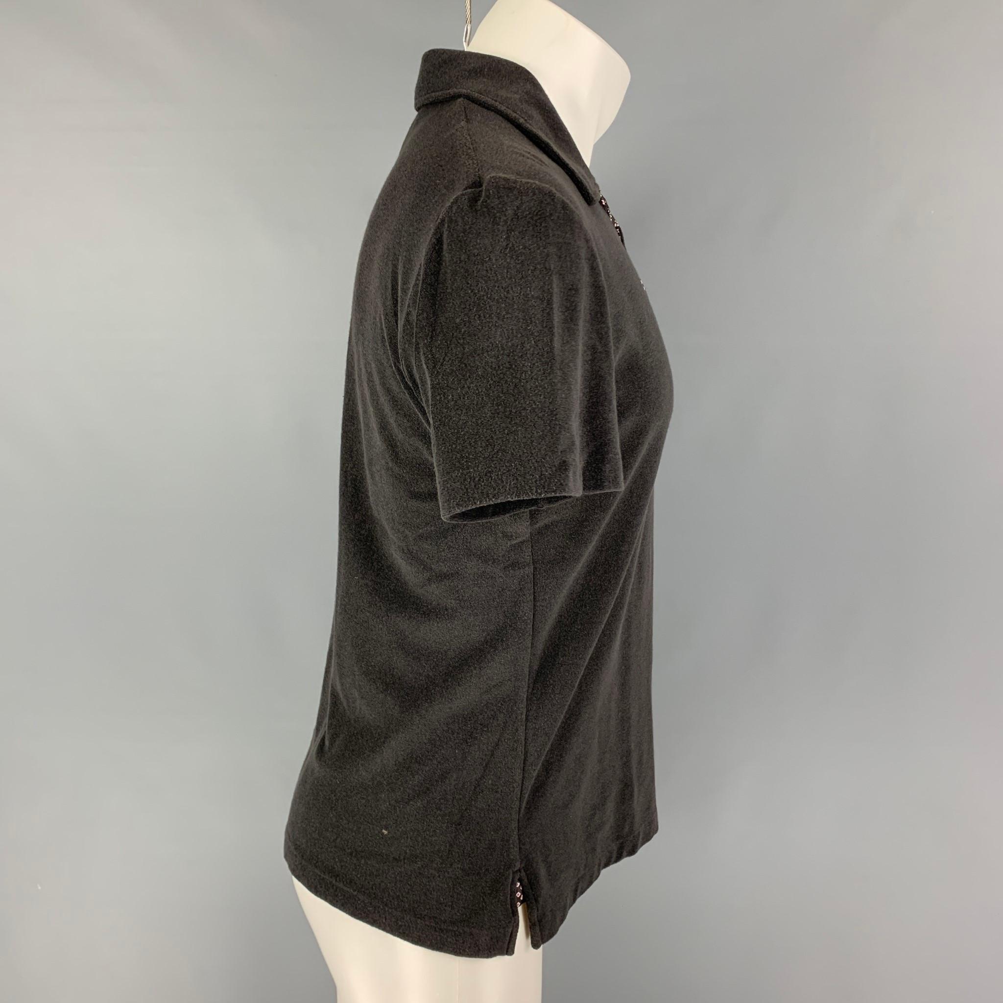 YVES SAINT LAURENT polo comes in a gray cotton featuring a spread collar, silk trim, gold tone logo emblem, and a half buttoned closure. Made in Italy. 

Good Pre-Owned Condition. Moderate discoloration at shoulders. As-Is.
Marked: