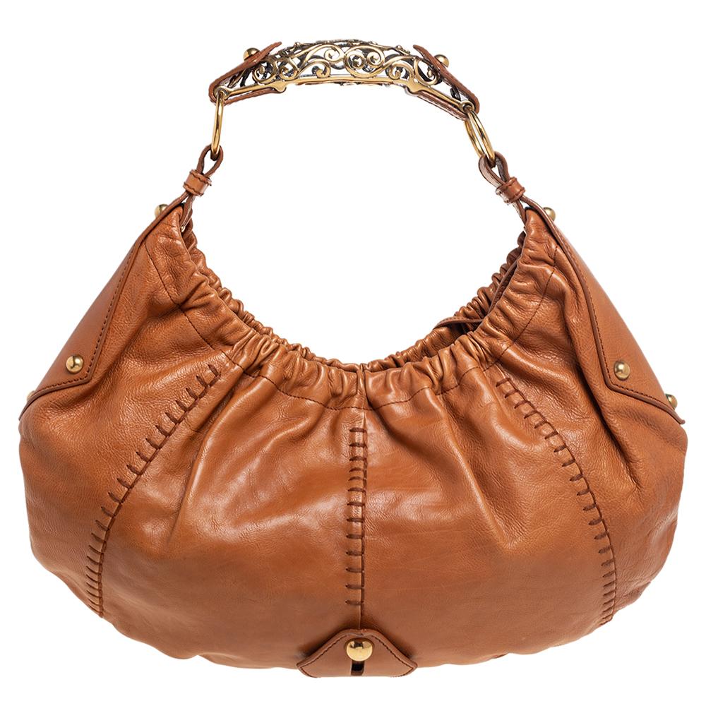 You will love to have this Yves Saint Laurent Mombasa hobo. Crafted from tan leather and held by a unique filigree handle, the bag is a beauty. The interior is lined with satin and sized to house your essentials with ease.

Includes: Original Dustbag
