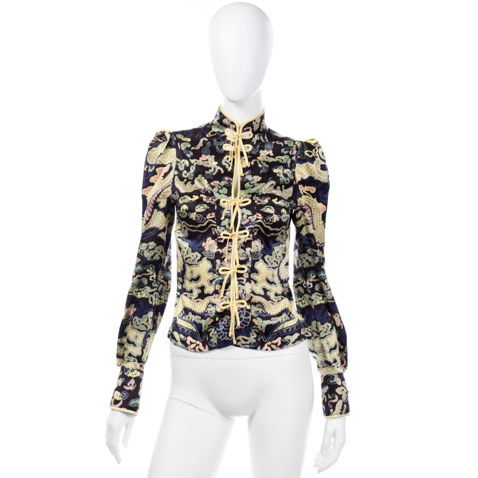 This is a beautiful YSL Rive Gauche Chinoiserie inspired silk printed blouse in various shades of blue, green, yellow and a touch of pink. This fabulous YSL top has a high neck and silk ribbon loops down the center front. The front of the blouse has