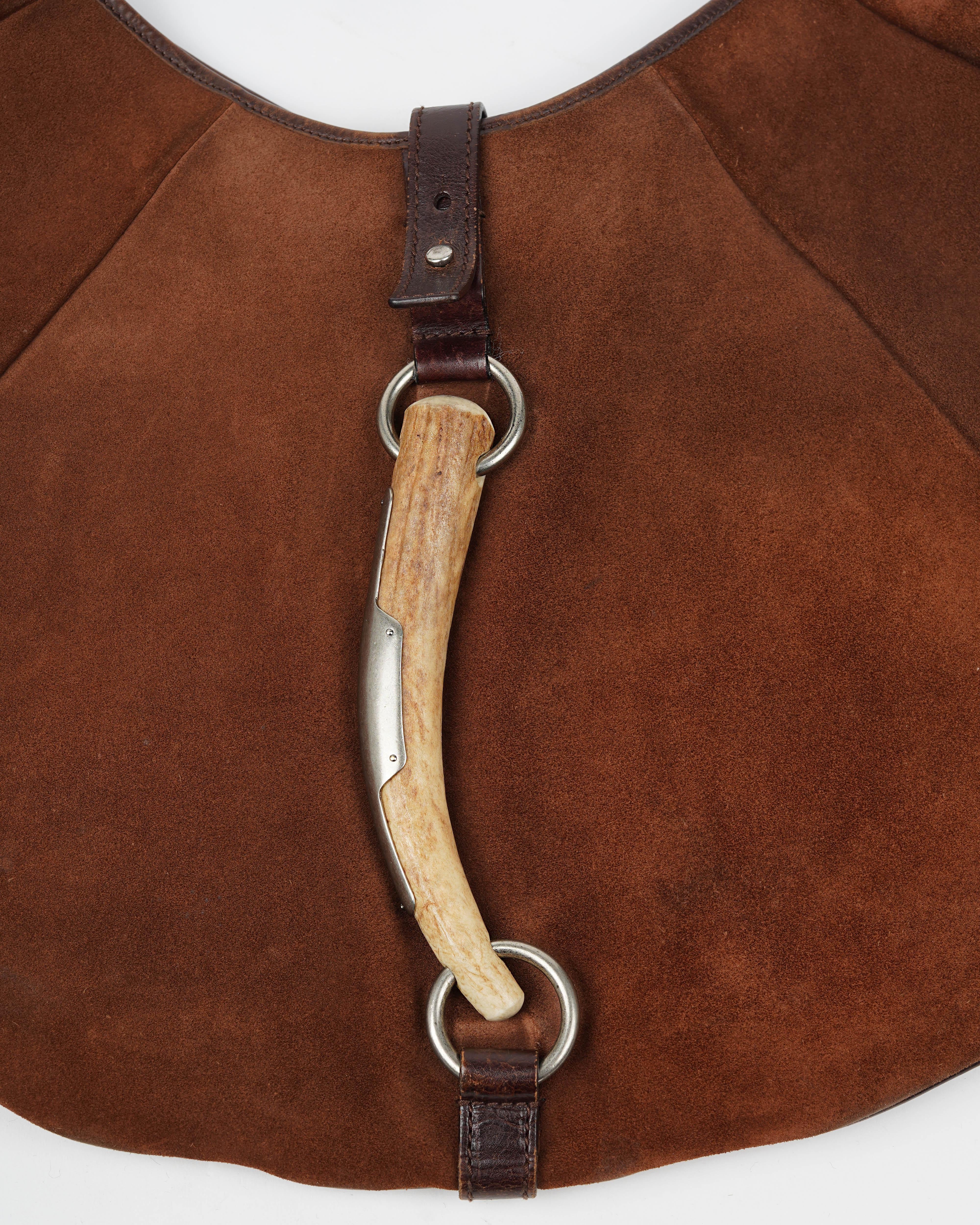 Design iconico dell'era Tom Ford for Yves Saint Laurent, la borsa hobo Mombasa rimane uno degli accessori più collezionabili e caratteristici della maison. Questa rara versione in pelle scamosciata marrone presenta finiture in pelle scura e il