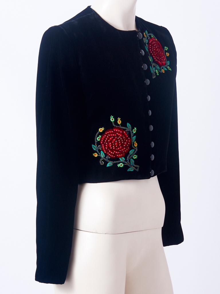 Yves Saint Laurent, RIve Gauche, black velvet, cropped jacket, having no collar, and looped, jet button closures. Jacket has velvet embroidered, rose flower motifs, asymmetrically placed in the front and in the center of the back. There are beaded